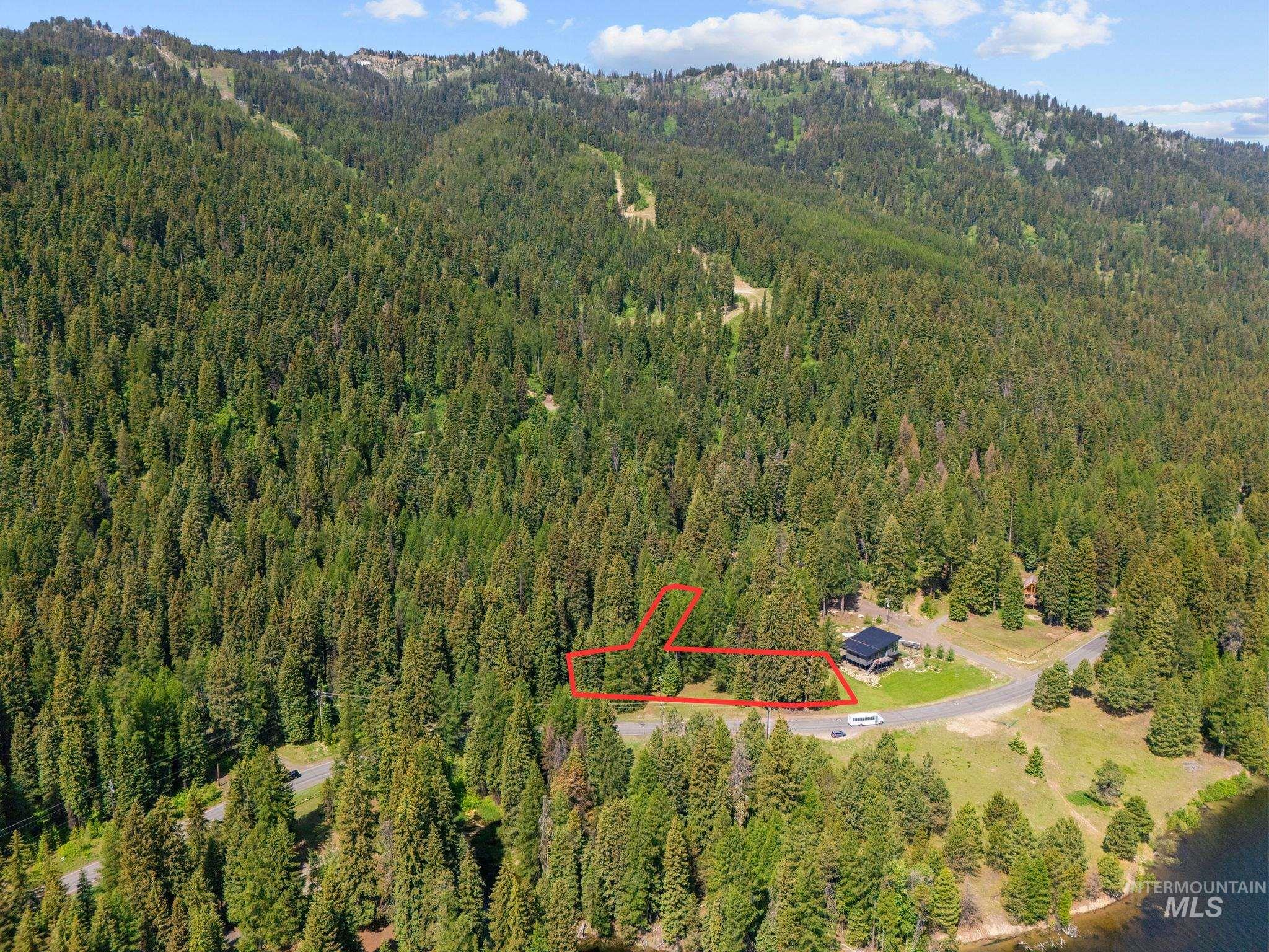 Aerial view of property and surrounding area with property boundaries highlighted and a mountain backdrop