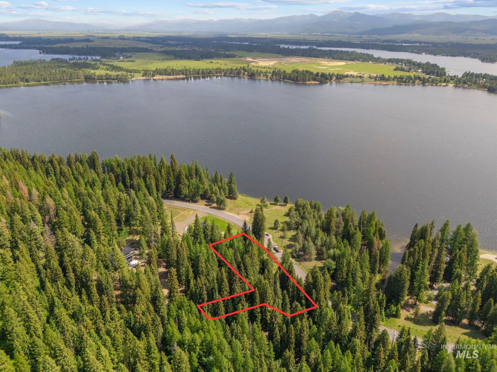 Aerial view of property and surrounding area featuring a water and mountain view and property parcel outlined