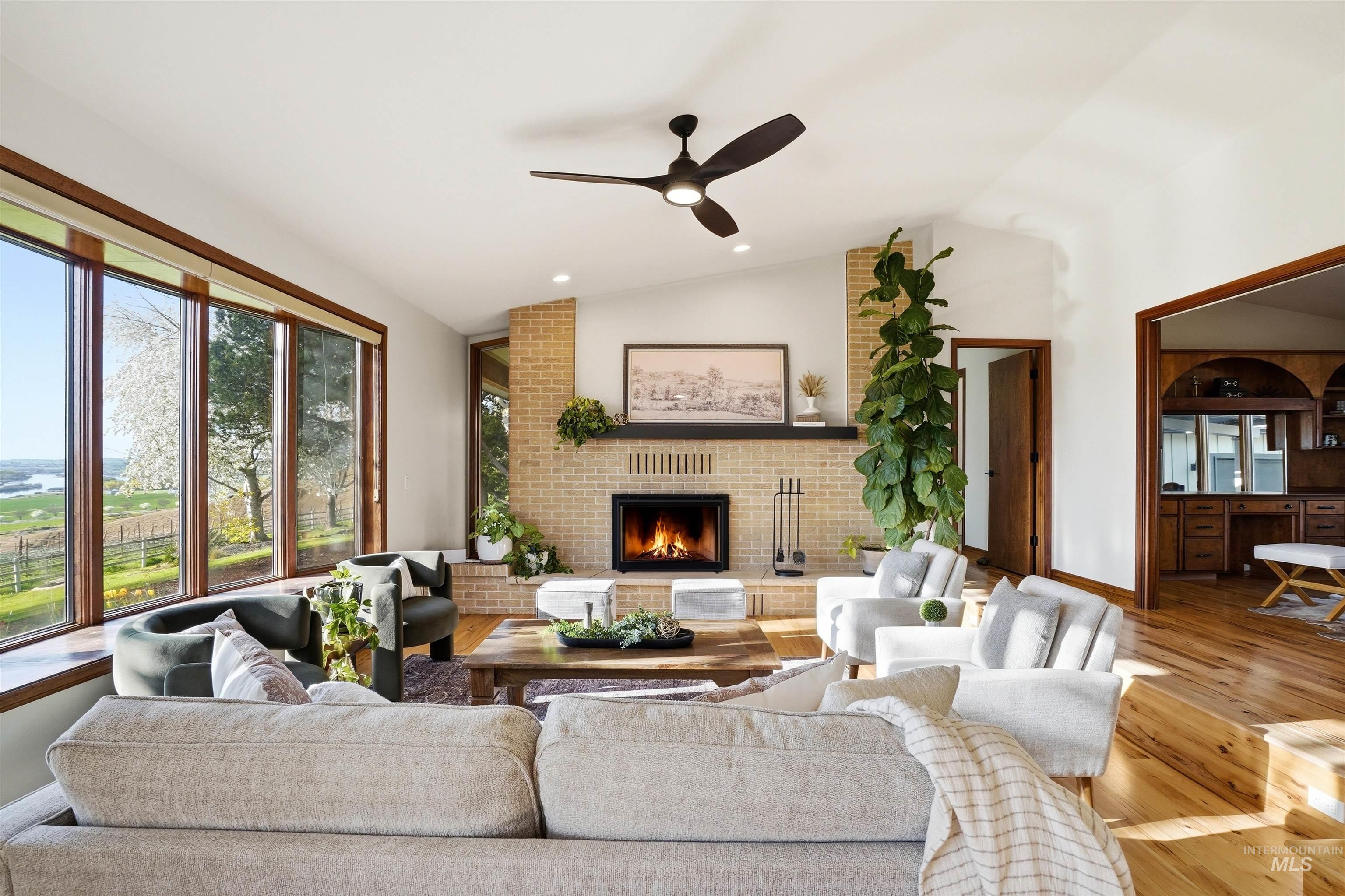 Living area with ceiling fan, vaulted ceiling, a brick fireplace, hardwood / wood-style flooring, and recessed lighting