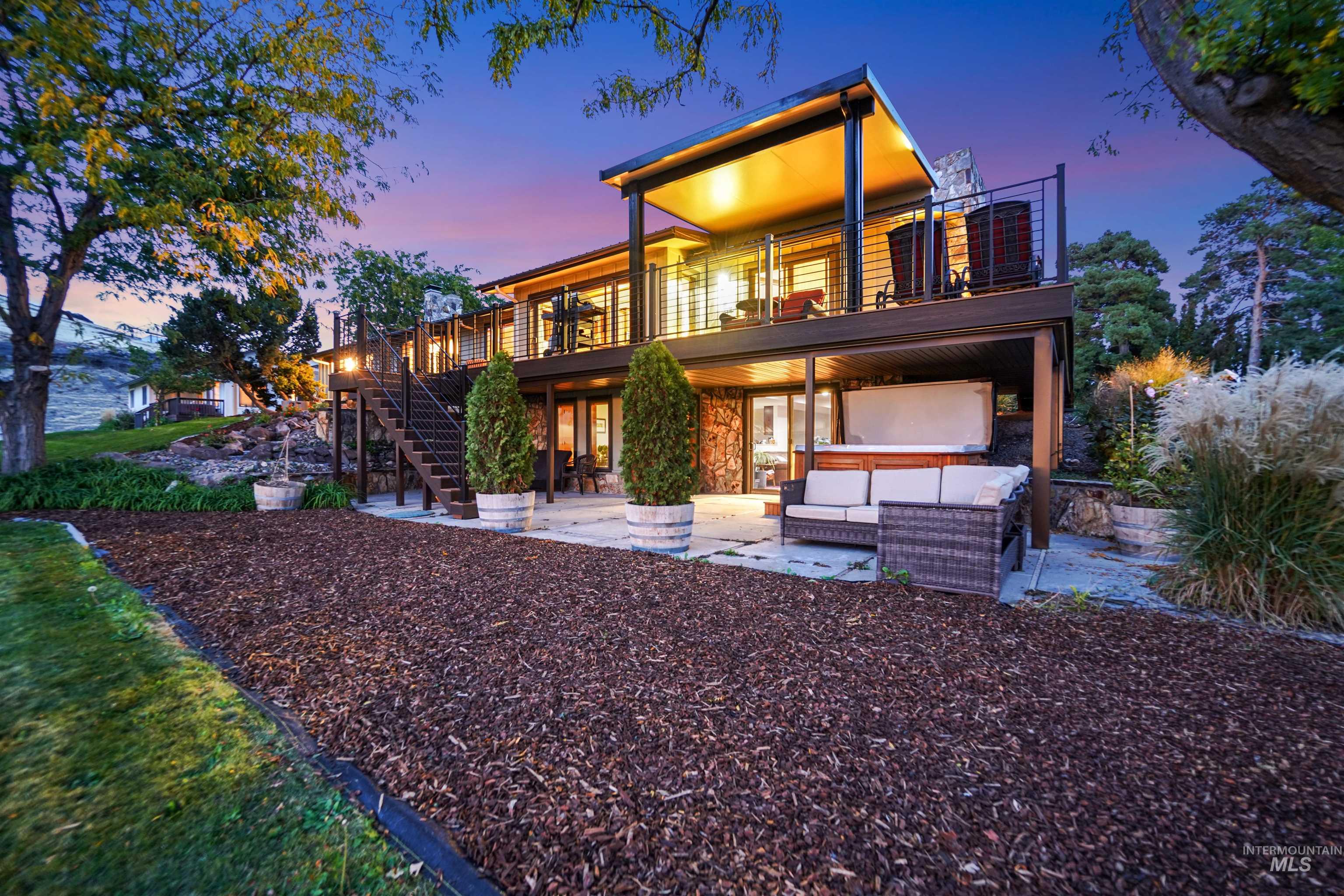 Back of property at dusk with a patio, an outdoor lounge area, a wooden deck, and stone siding