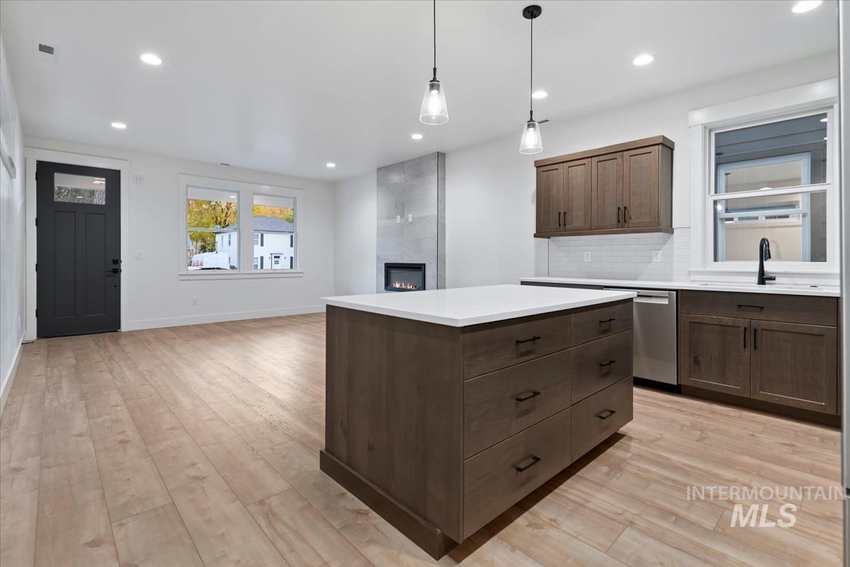 Kitchen with a kitchen island, pendant lighting, backsplash, recessed lighting, and a fireplace