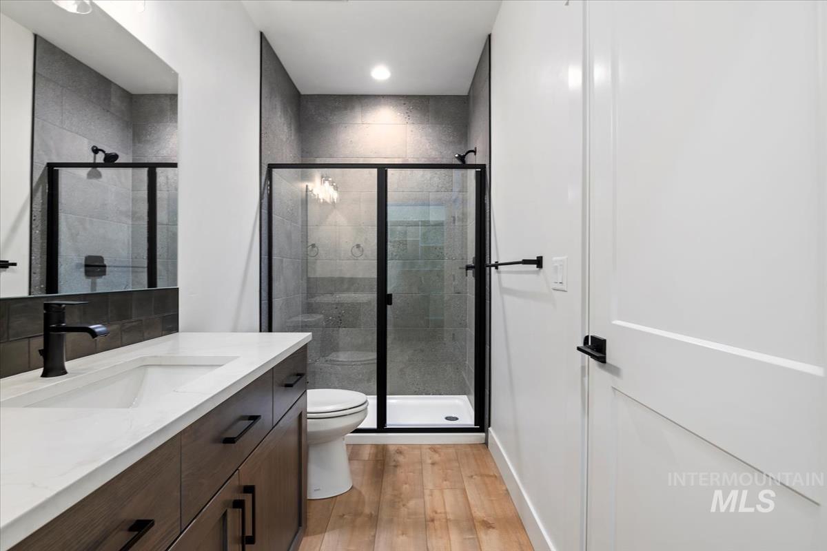Bathroom with vanity, light wood-style floors, a shower stall, and recessed lighting