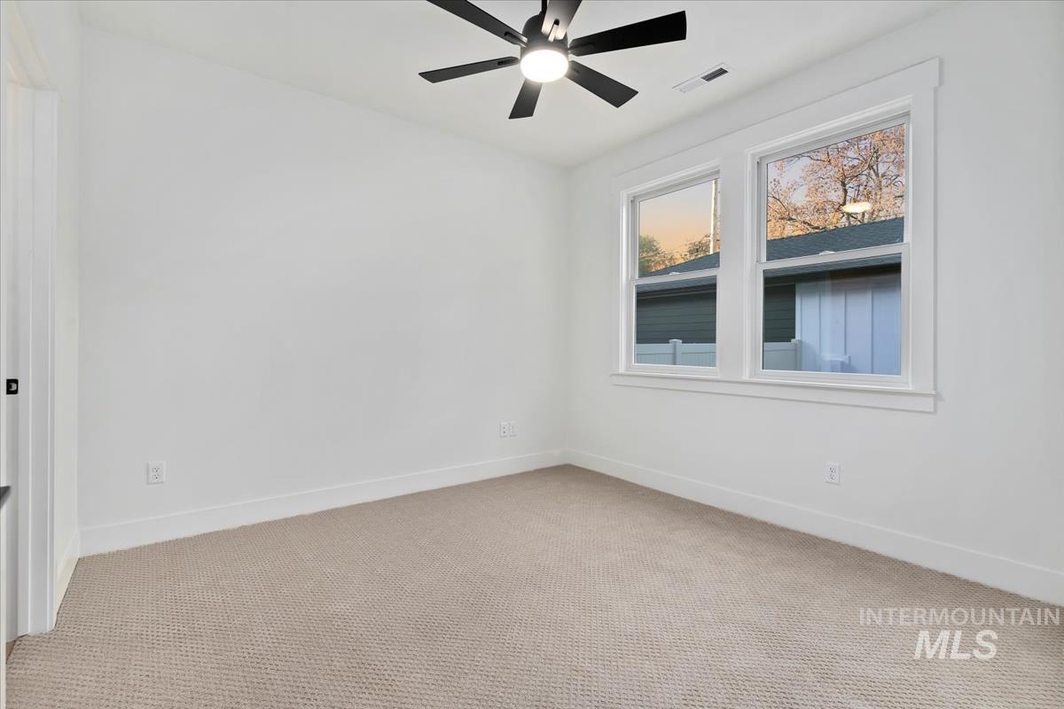 Carpeted spare room with baseboards and a ceiling fan