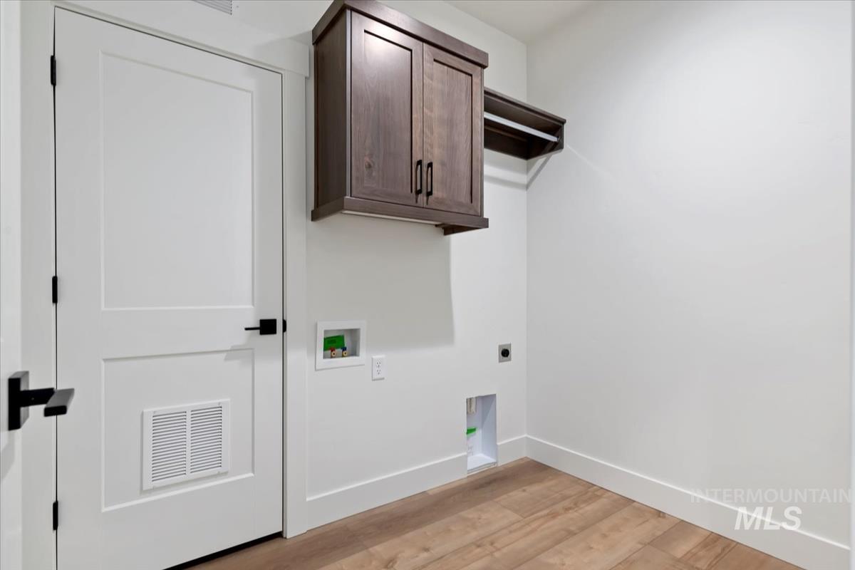 Laundry area featuring light wood-style flooring, cabinet space, hookup for an electric dryer, and washer hookup