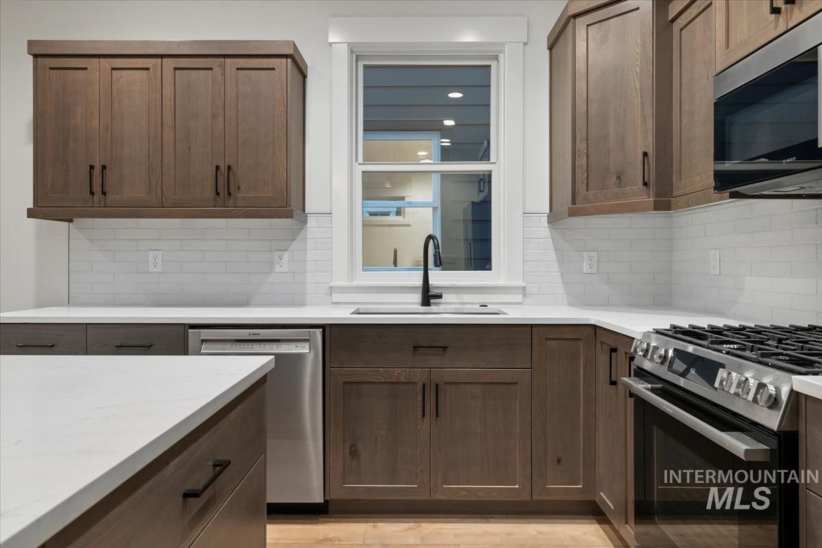 Kitchen with appliances with stainless steel finishes, decorative backsplash, and light stone countertops