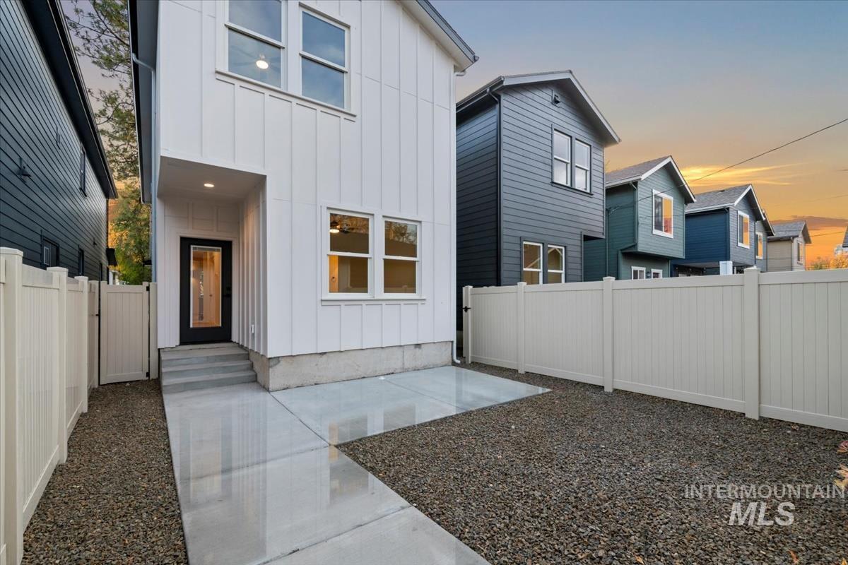 Rear view of house featuring board and batten siding, a fenced backyard, and a residential view