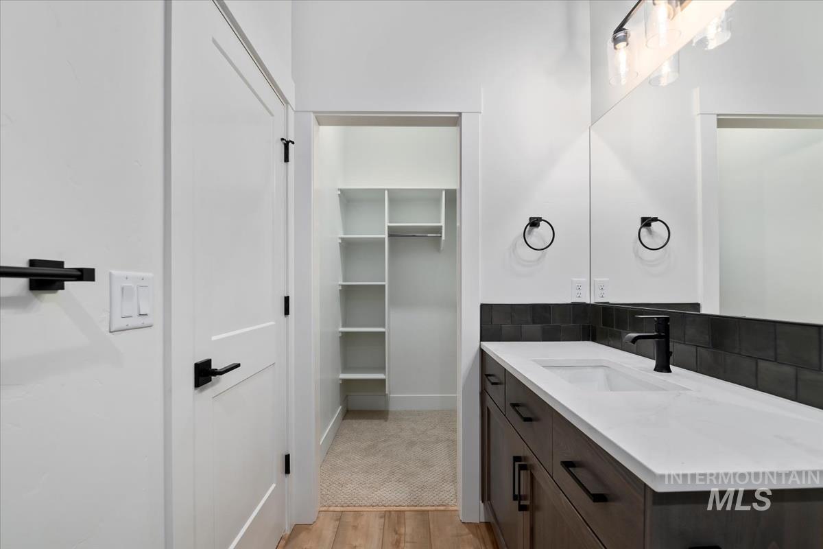 Bathroom with vanity, light wood finished floors, and a spacious closet