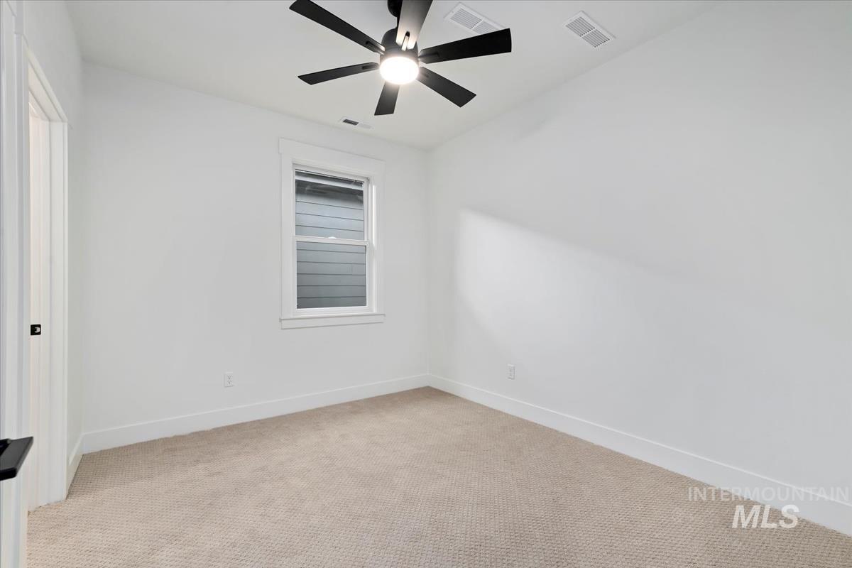 Empty room with light colored carpet and a ceiling fan