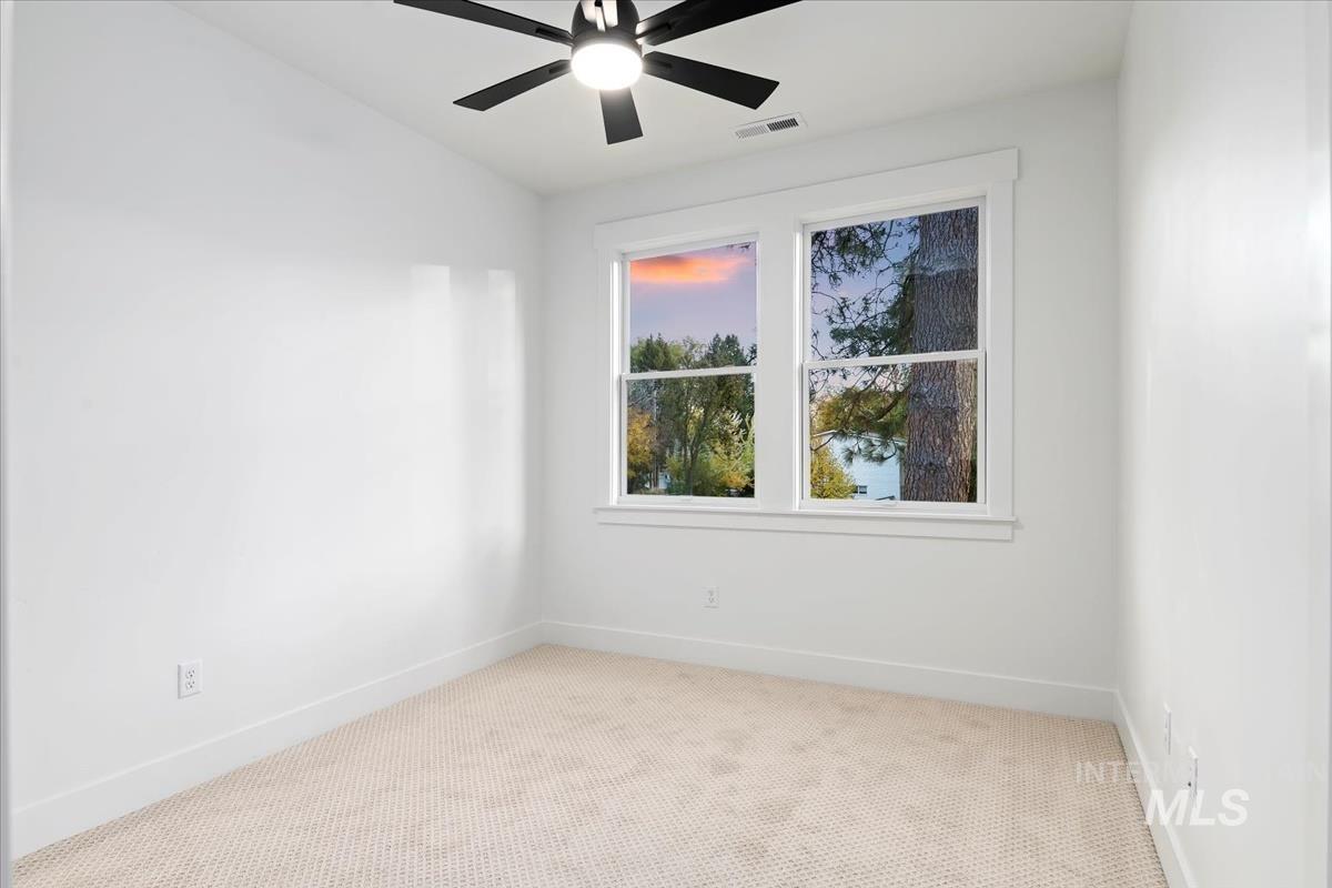 Carpeted empty room featuring baseboards and ceiling fan
