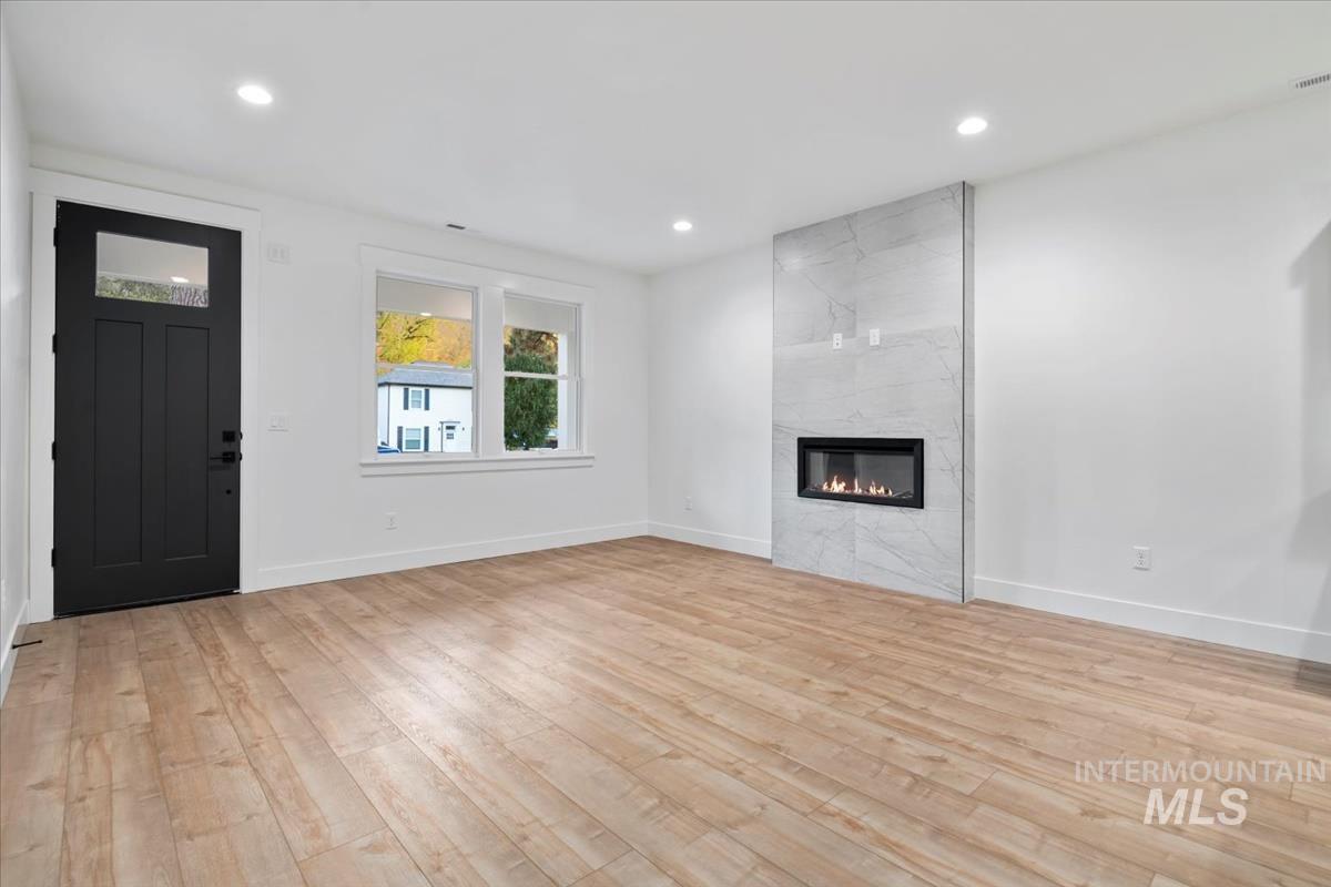 Unfurnished living room featuring recessed lighting, light wood-style flooring, and a fireplace