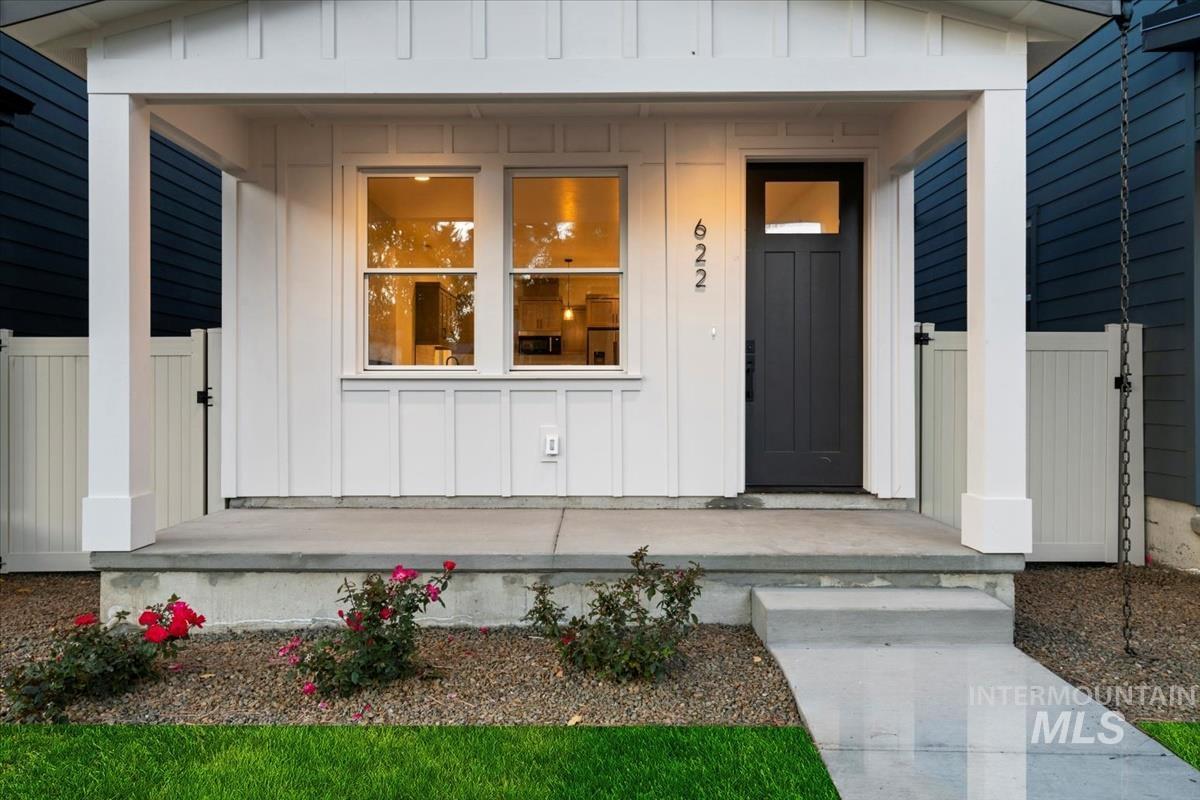 View of exterior entry with board and batten siding, a porch, and a gate