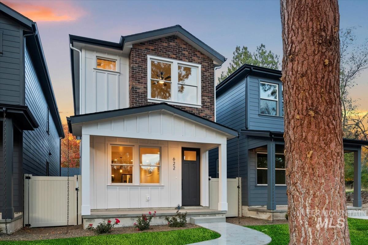 Contemporary home with board and batten siding, a porch, brick siding, and a gate