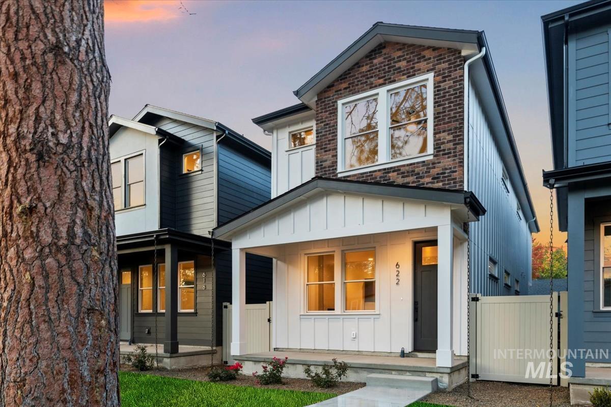 View of front of home featuring board and batten siding, a porch, a gate, and brick siding