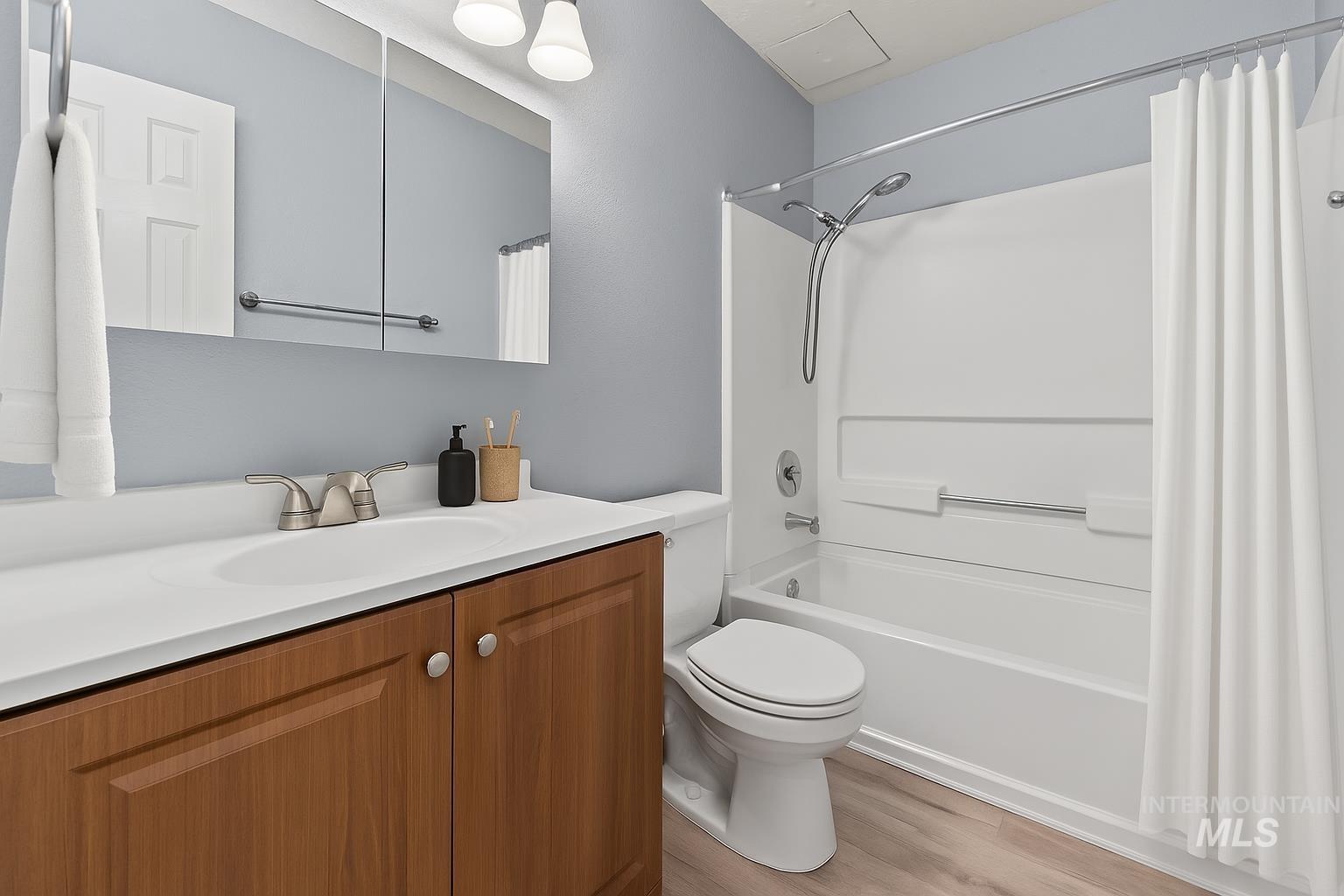 Bathroom with vanity, shower / bath combo with shower curtain, and light wood-style floors