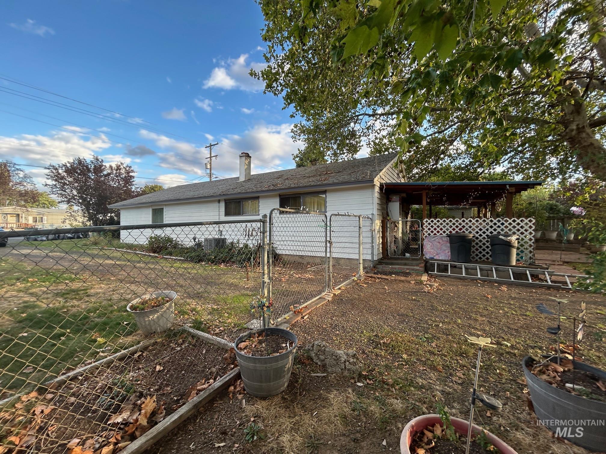 Rear view of house featuring a gate, a chimney, and a vegetable garden