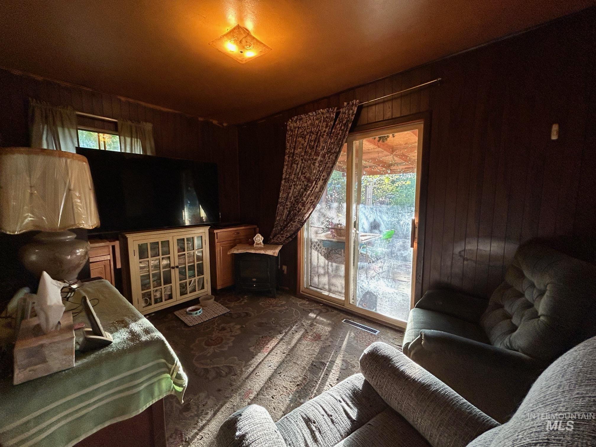 Bedroom featuring wooden walls, access to outside, and dark colored carpet