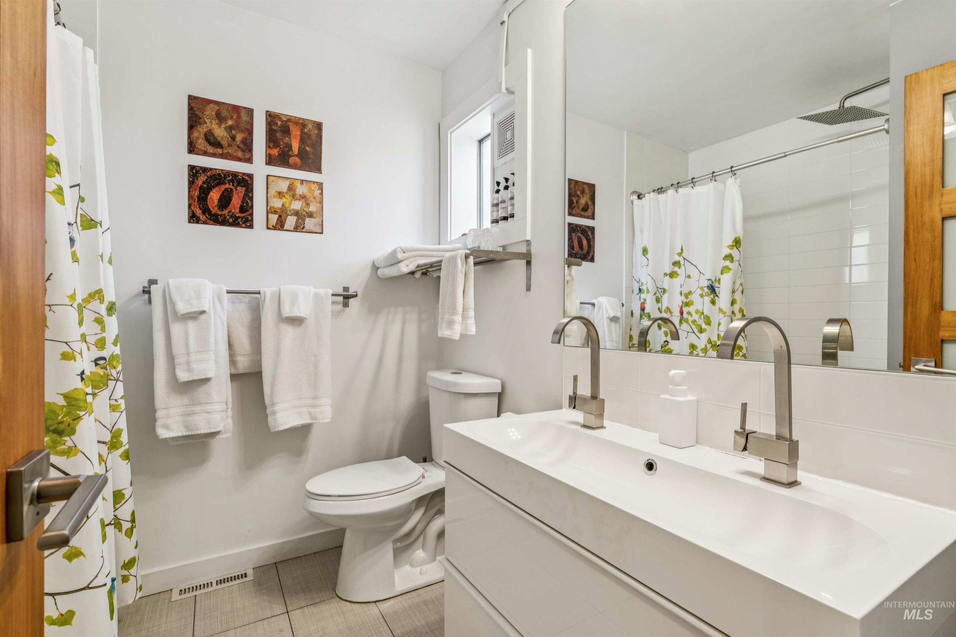 Full bath featuring vanity, light tile patterned floors, and a shower with curtain