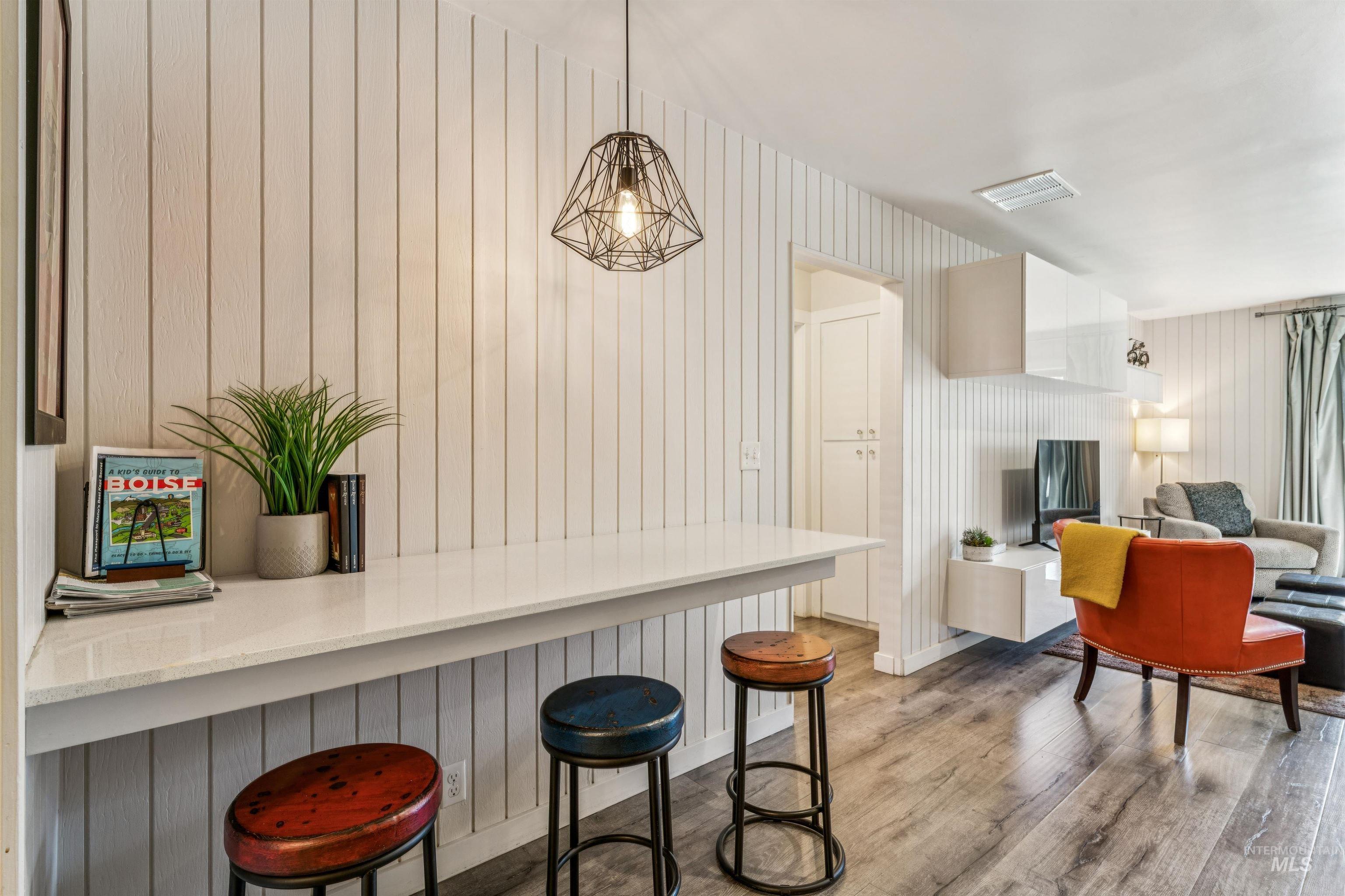 Kitchen featuring light wood-type flooring, a kitchen breakfast bar, light stone countertops, decorative light fixtures, and open floor plan