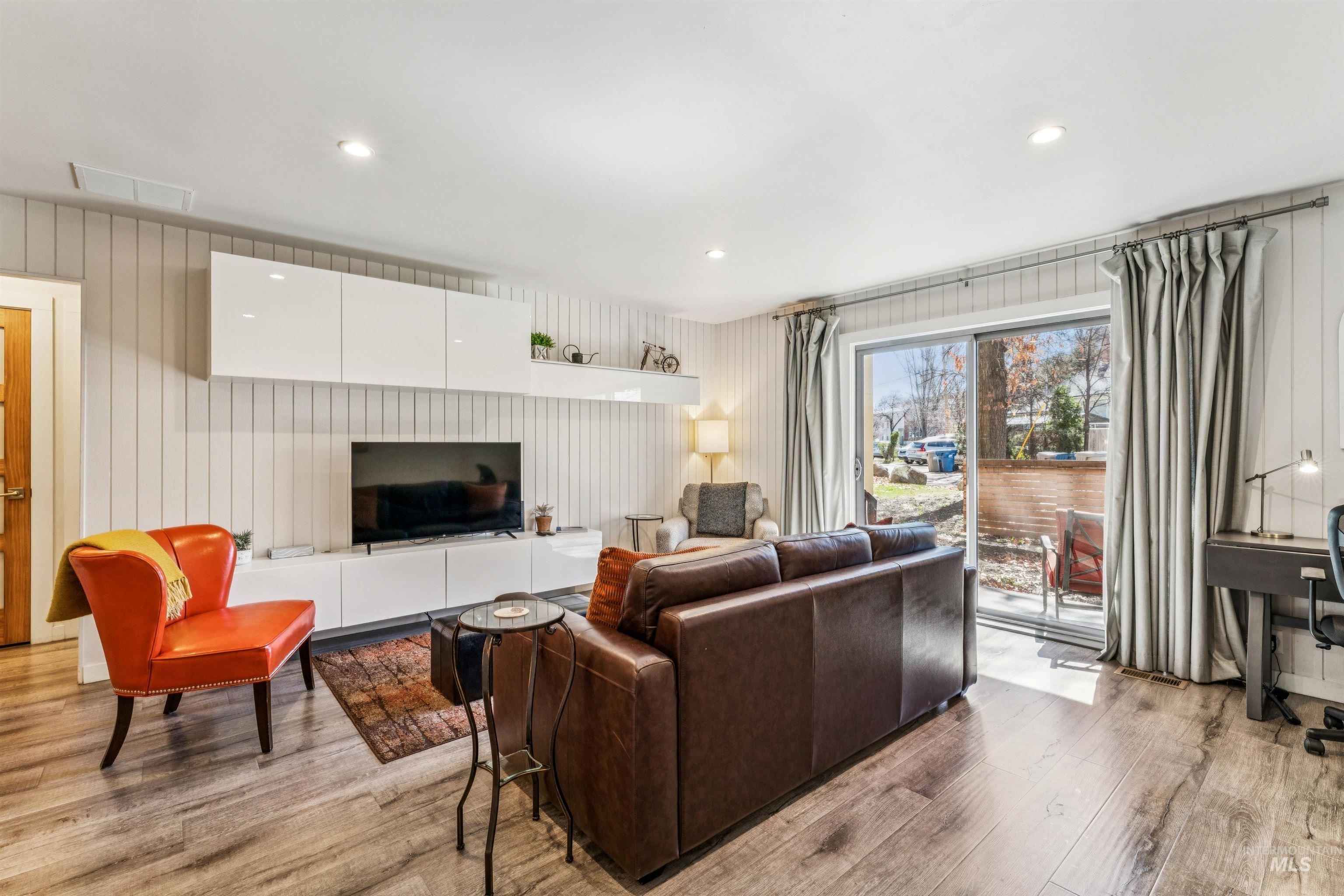 Living area with light wood-style floors, recessed lighting, and wooden walls