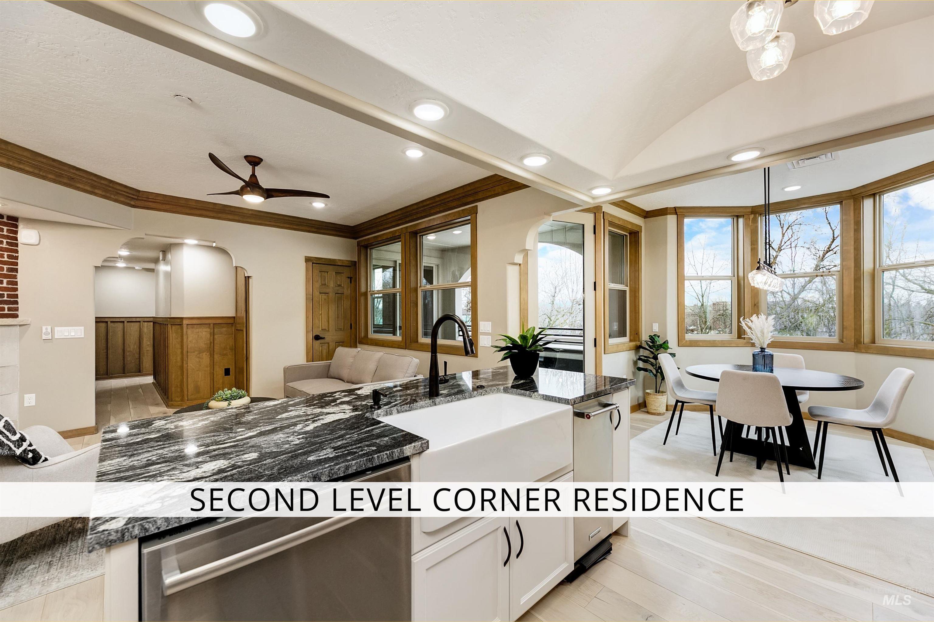 Kitchen featuring dark stone countertops, arched walkways, crown molding, light wood-style flooring, and a ceiling fan