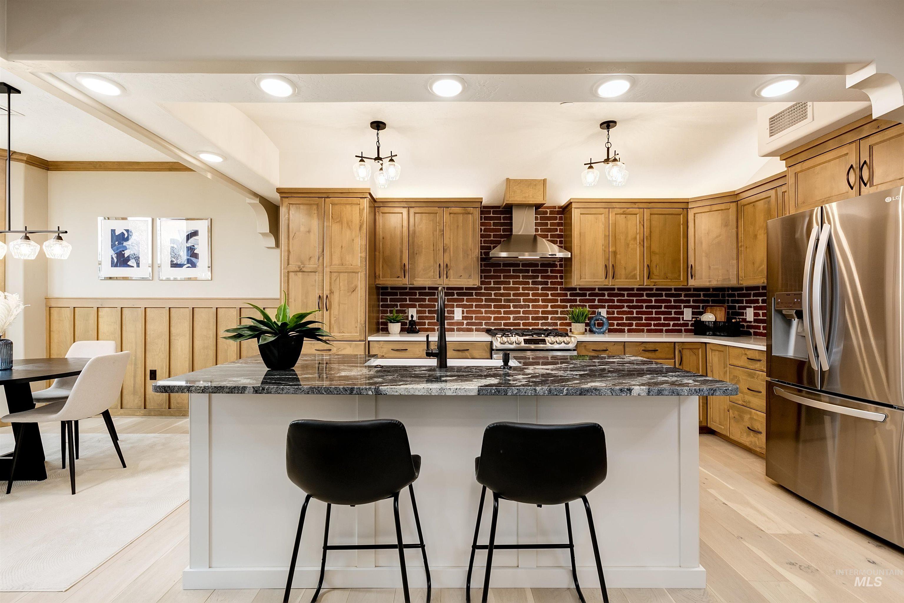 Kitchen with stainless steel appliances, a breakfast bar, wood finish cabinets, dark stone countertops, and crown molding