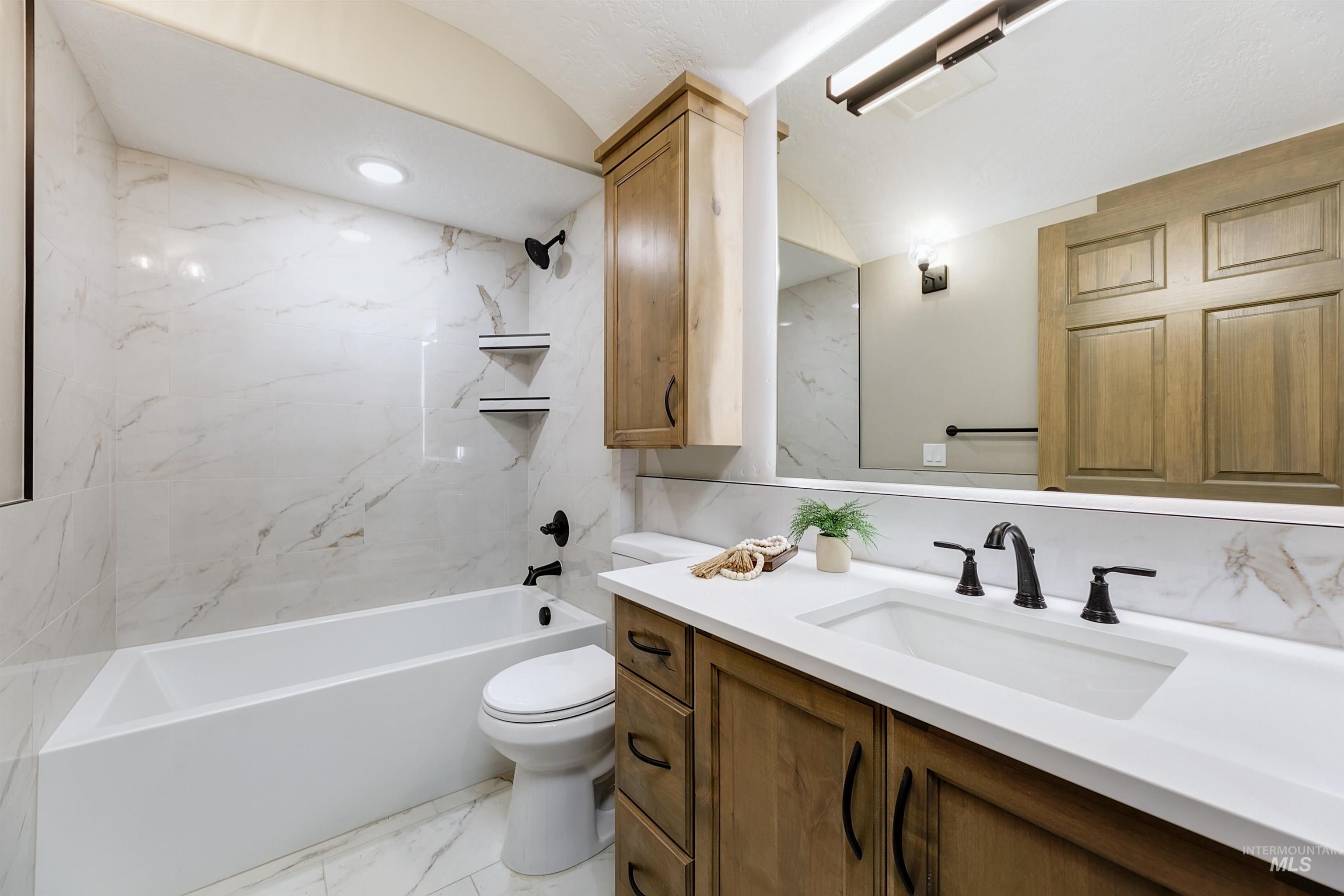 Bathroom featuring light marble finish floors, vanity, and shower / washtub combination