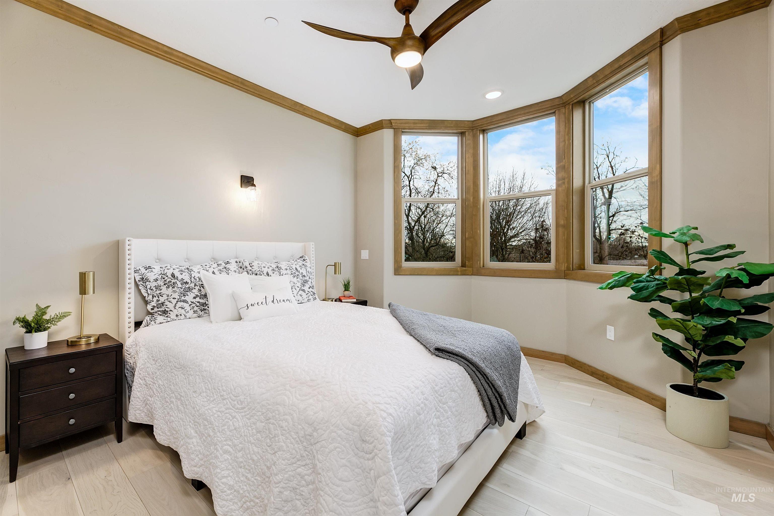 Bedroom featuring light wood finished floors, ceiling fan, and crown molding