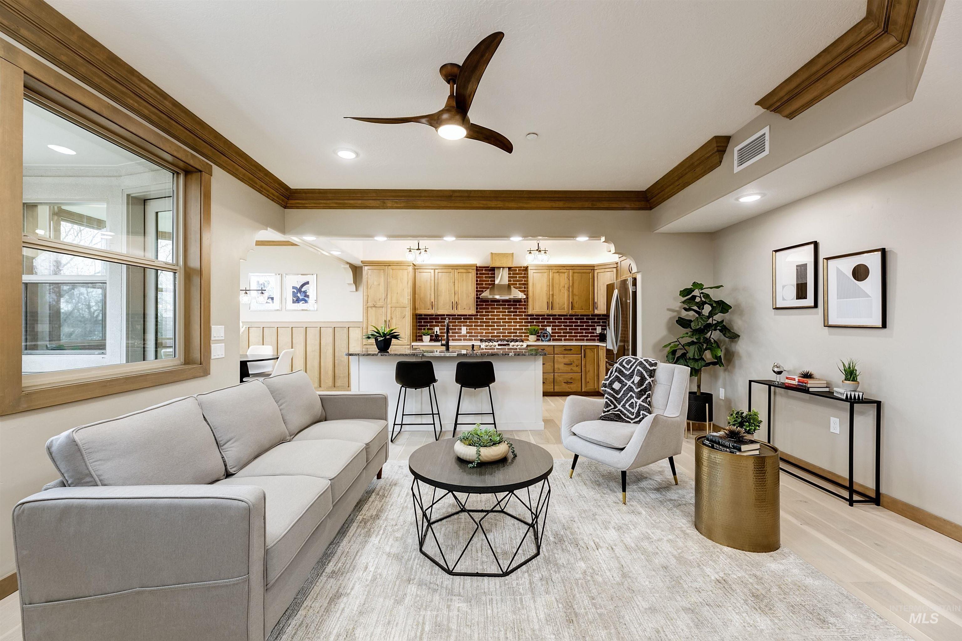 Living room with ceiling fan, crown molding, and light wood-type flooring