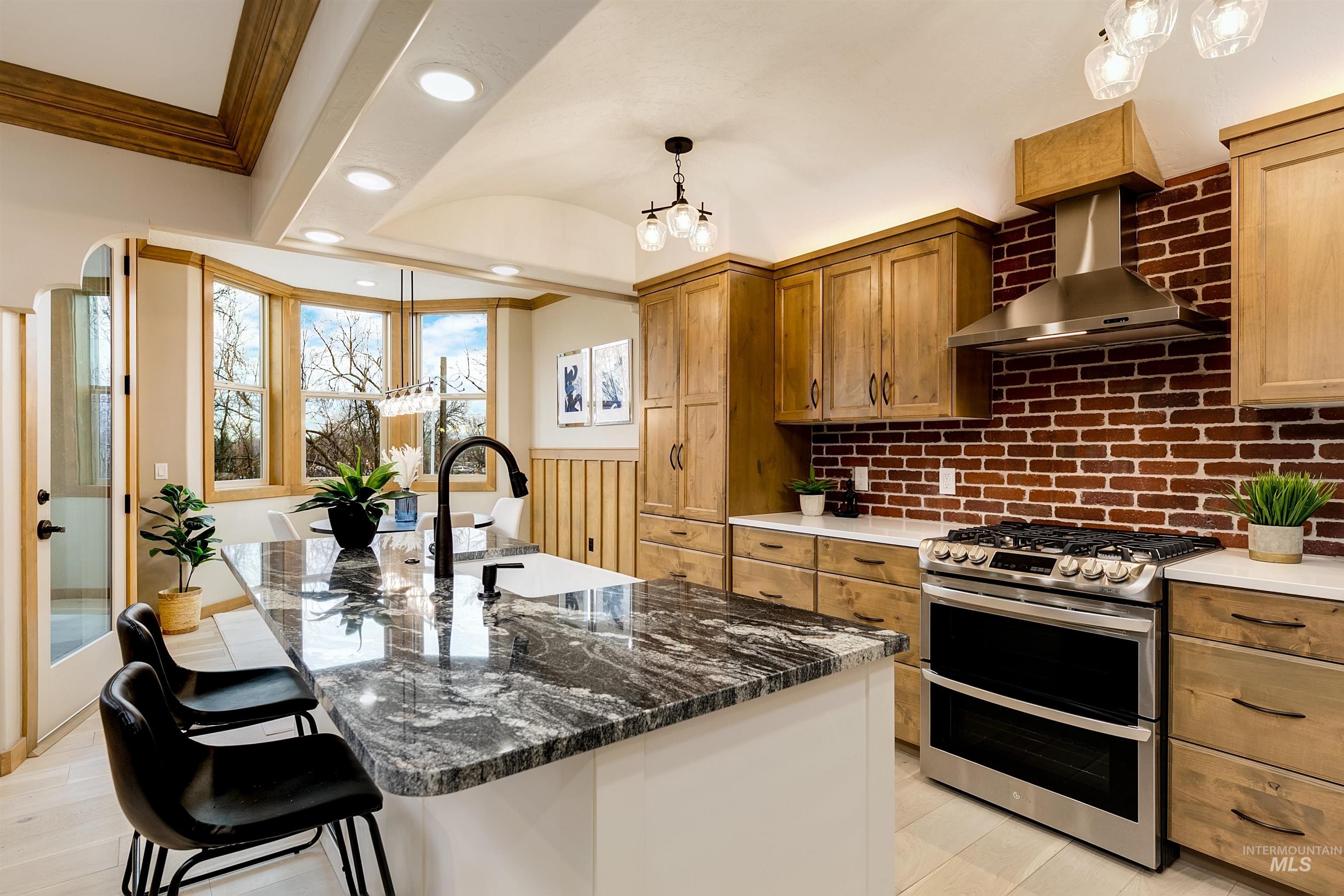 Kitchen with double oven range, a kitchen bar, dark stone countertops, a center island with sink, and two tone cabinets