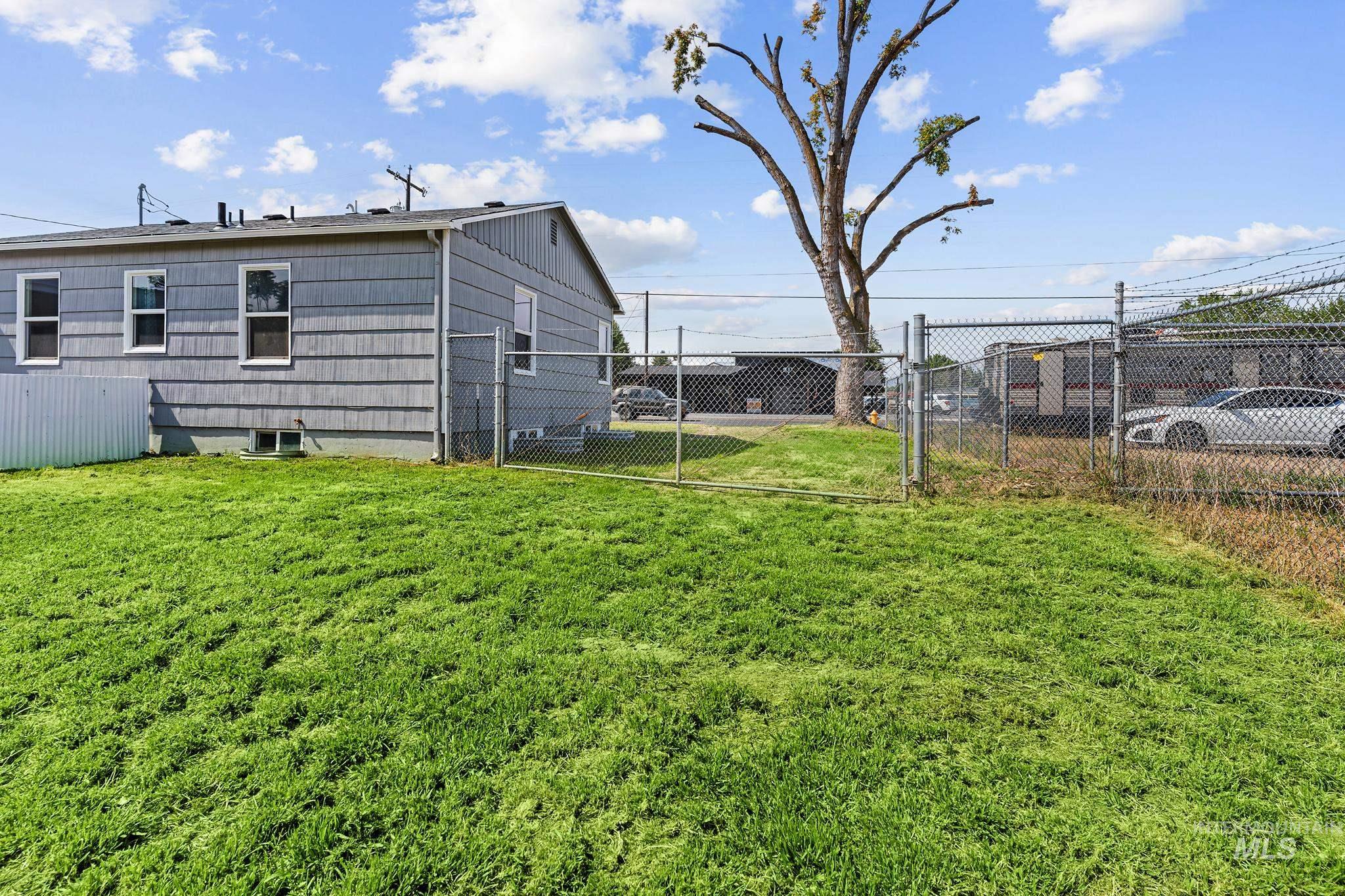 Expansive grassy yard with chain-link fencing enclosing the property