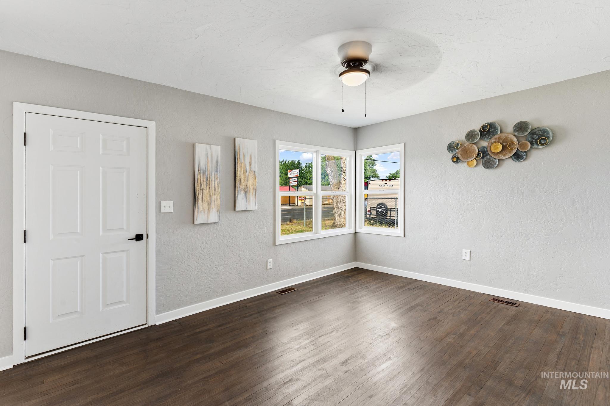 Spacious room featuring wood-finish flooring, light gray walls, and white trim