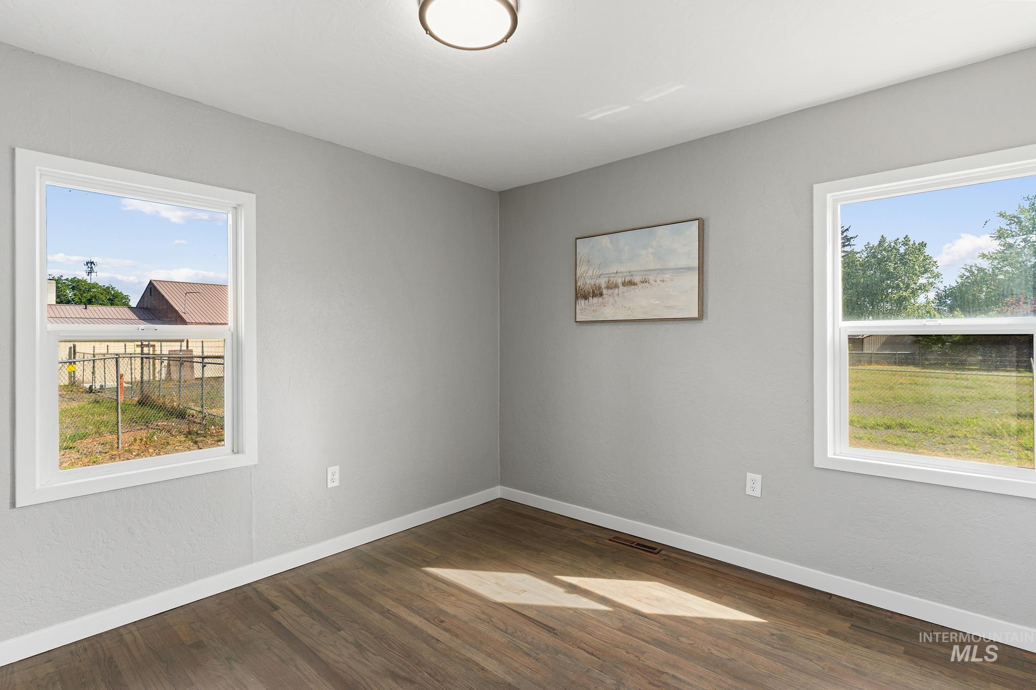 Room featuring wood-finish flooring, light grey walls, and white trim
