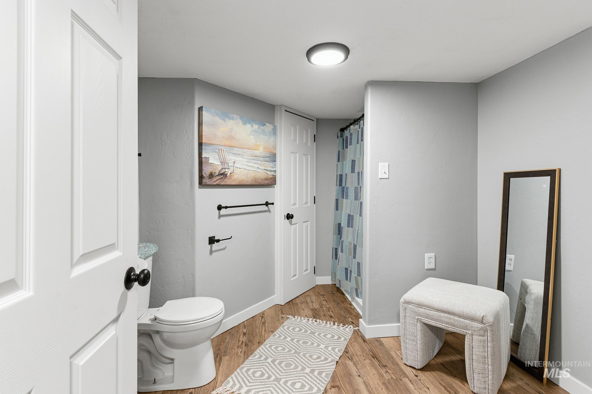 Bathroom featuring wood-finish flooring, a white toilet, recessed lighting, and a shower with a patterned curtain