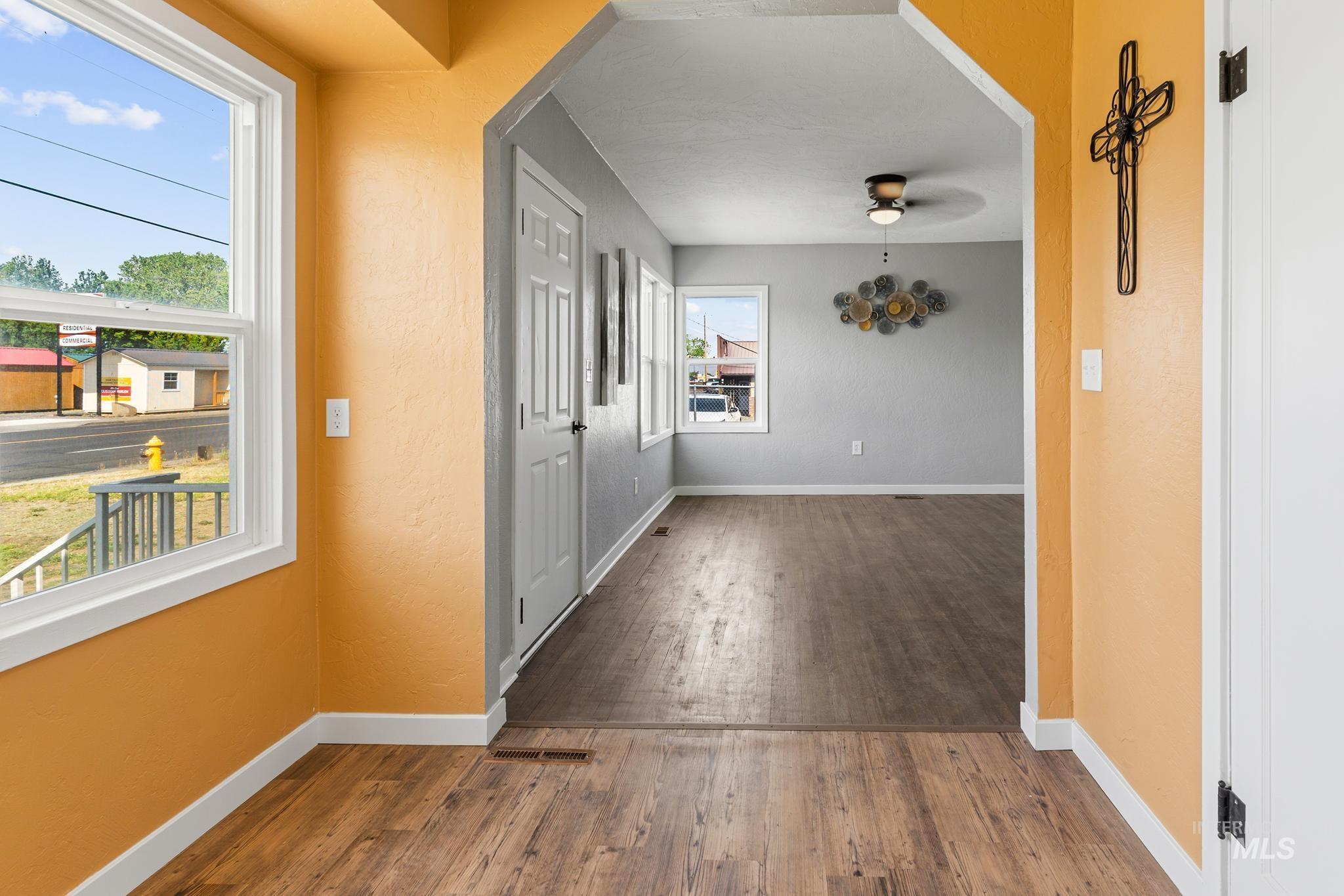 Open interior featuring wood-finish flooring, white trim, and a wide archway connecting two distinct areas