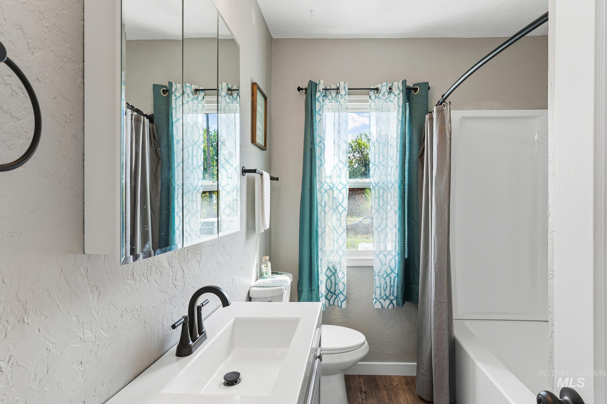 Bathroom featuring a white vanity with an integrated sink, matte black faucet, and medicine cabinet
