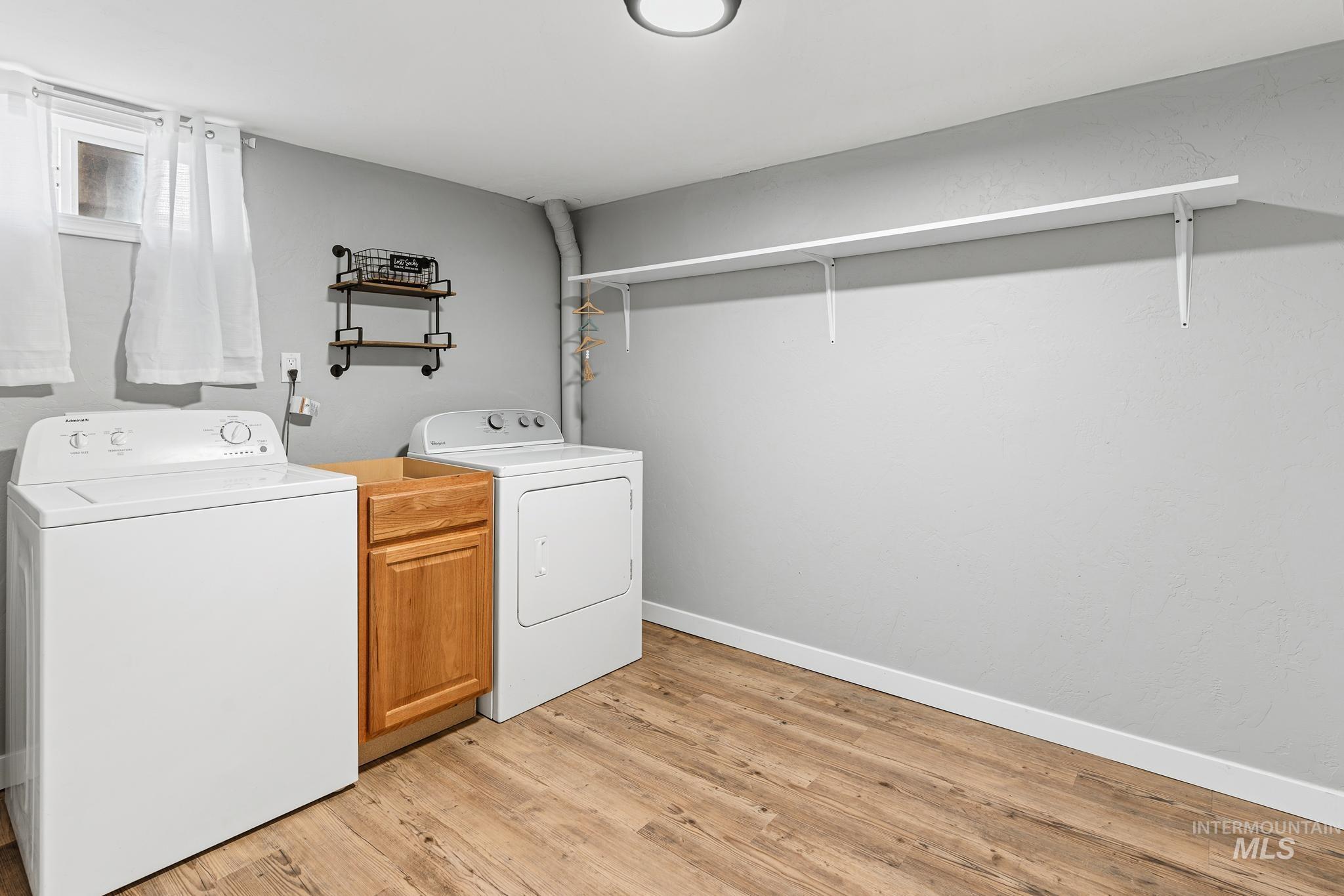 Dedicated laundry area featuring wood-finish flooring, light gray walls, and a built-in wood cabinet