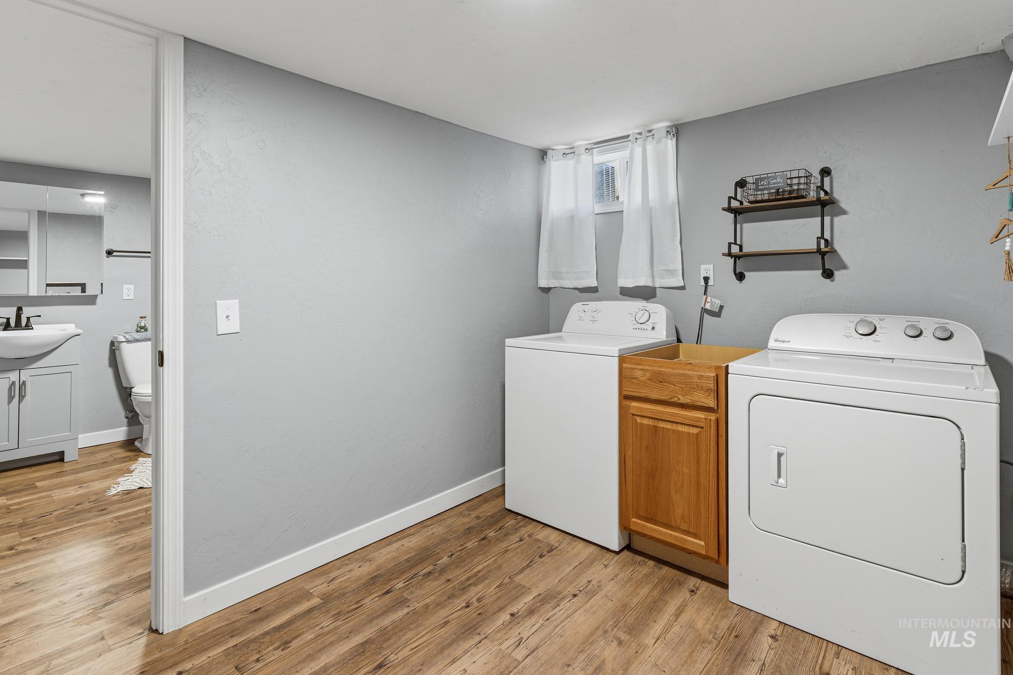Laundry area featuring wood-finish flooring, light gray walls, and a small window