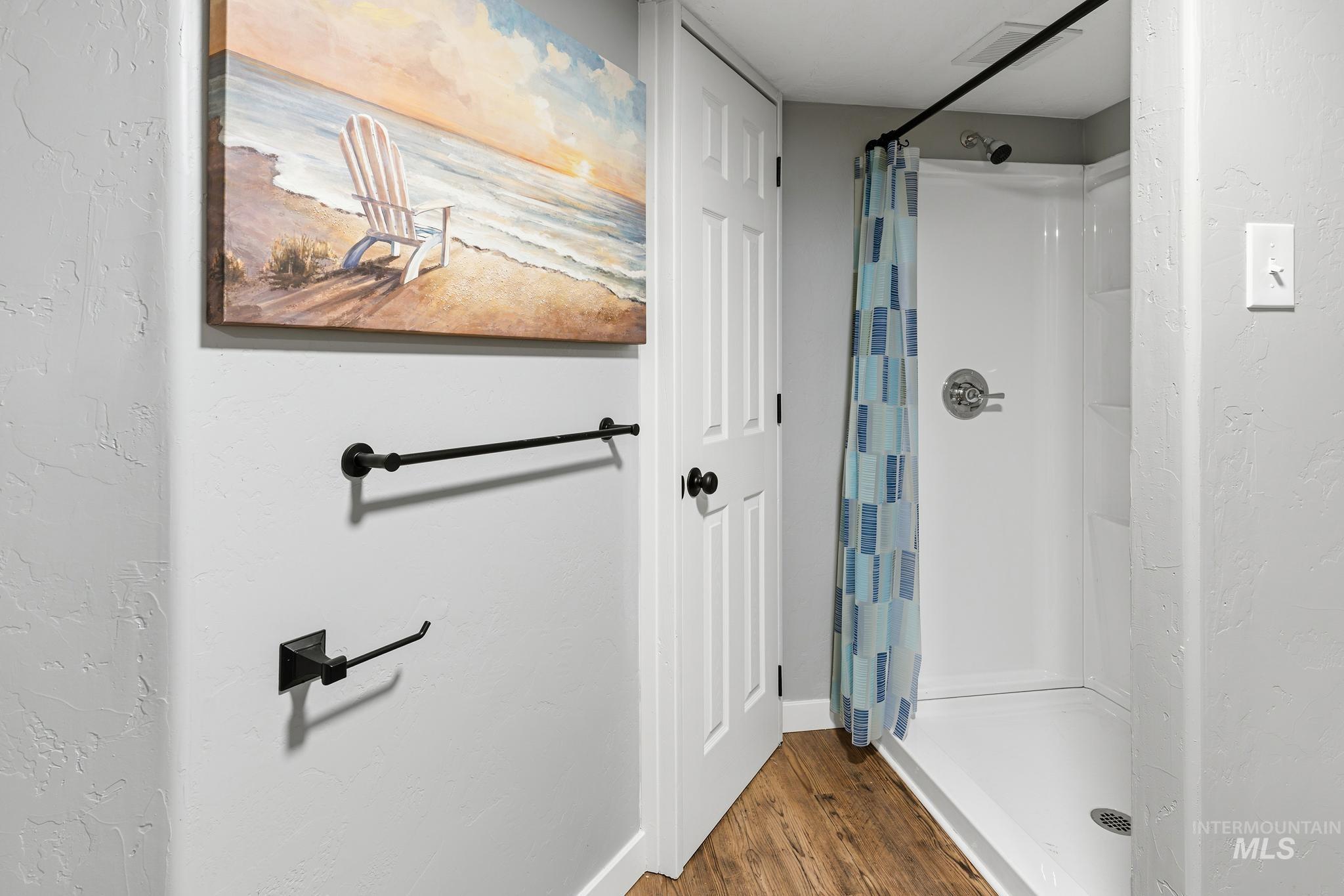 Walk-in shower with a chrome fixture and white surround