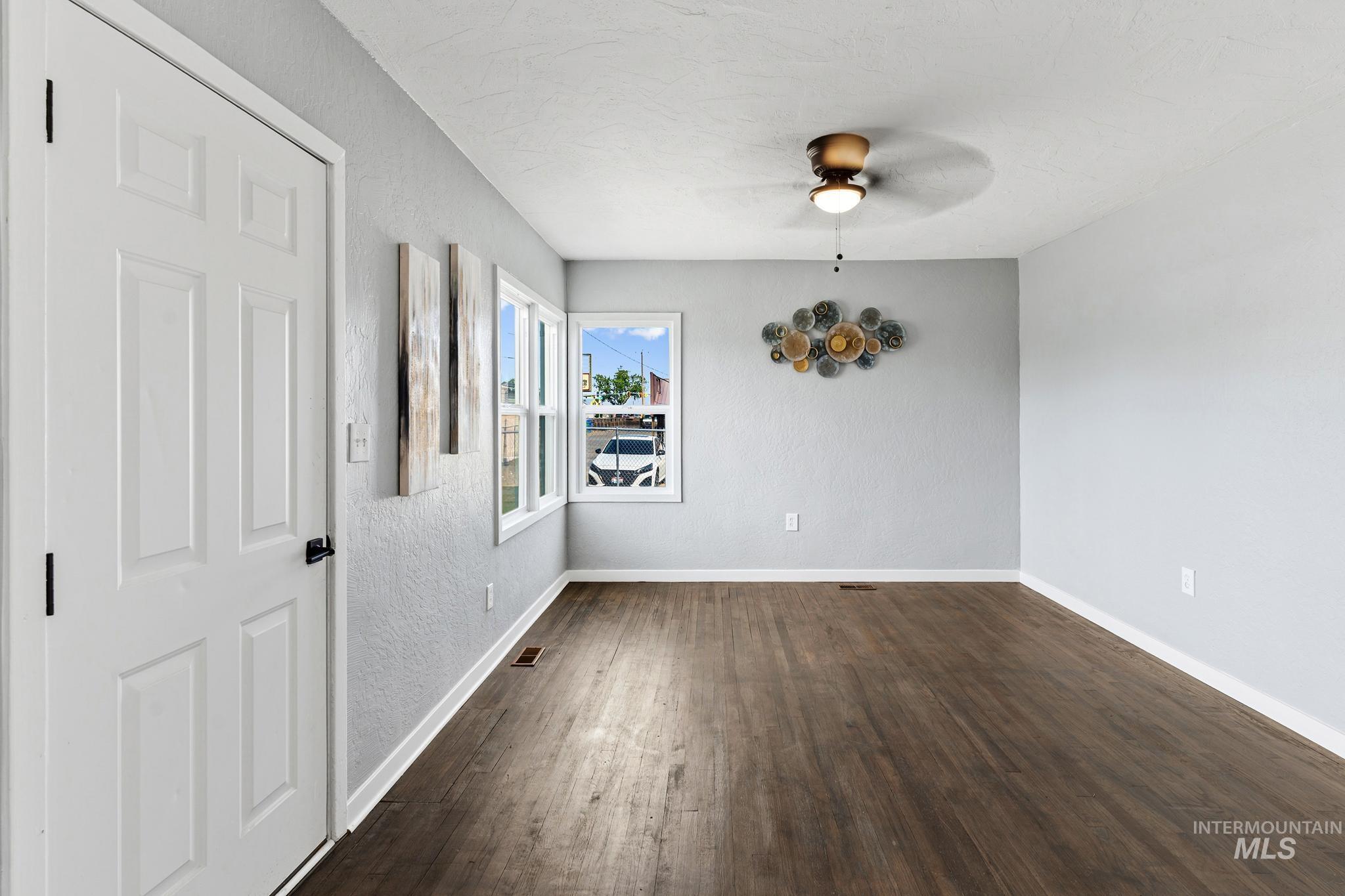Open living area featuring wood-finish flooring, light grey walls, and a multi-pane window configuration