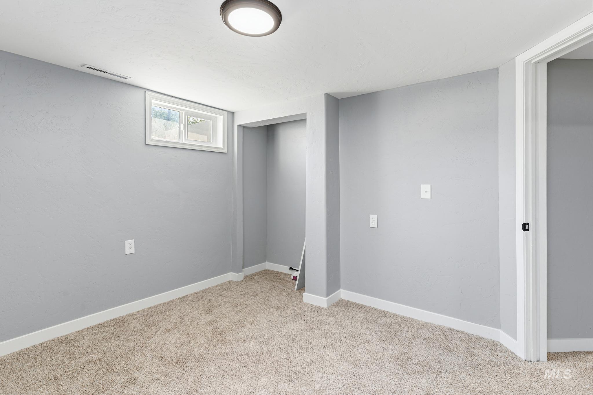 Carpeted room featuring light gray walls, white baseboards, and a white ceiling