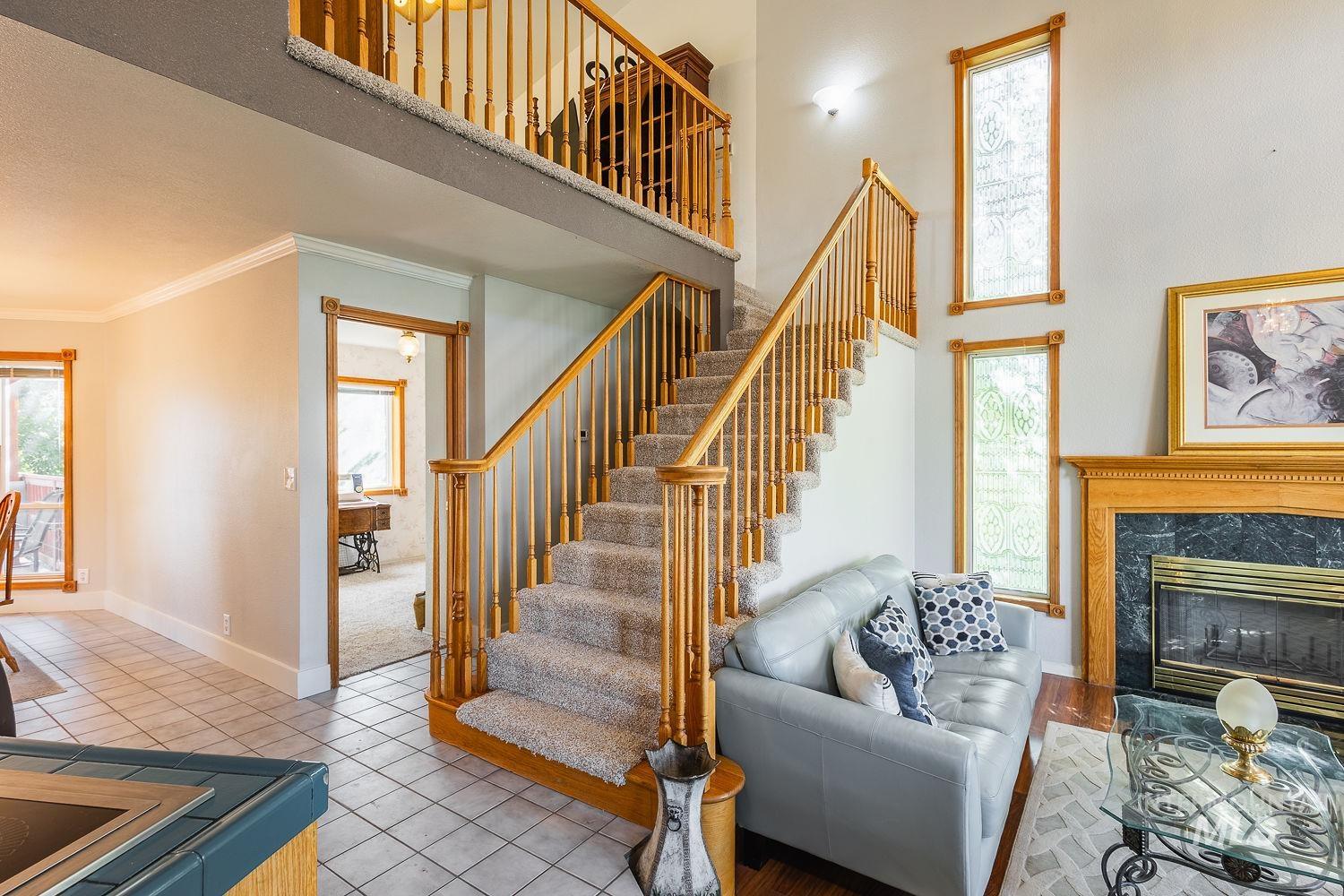 Living area with tile patterned flooring, a towering ceiling, a fireplace, ornamental molding, and stairway
