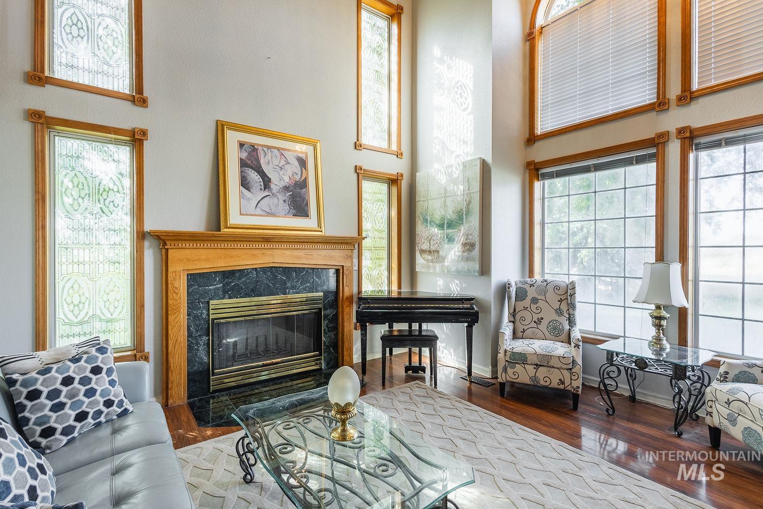 Living area with wood finished floors, a premium fireplace, and a high ceiling