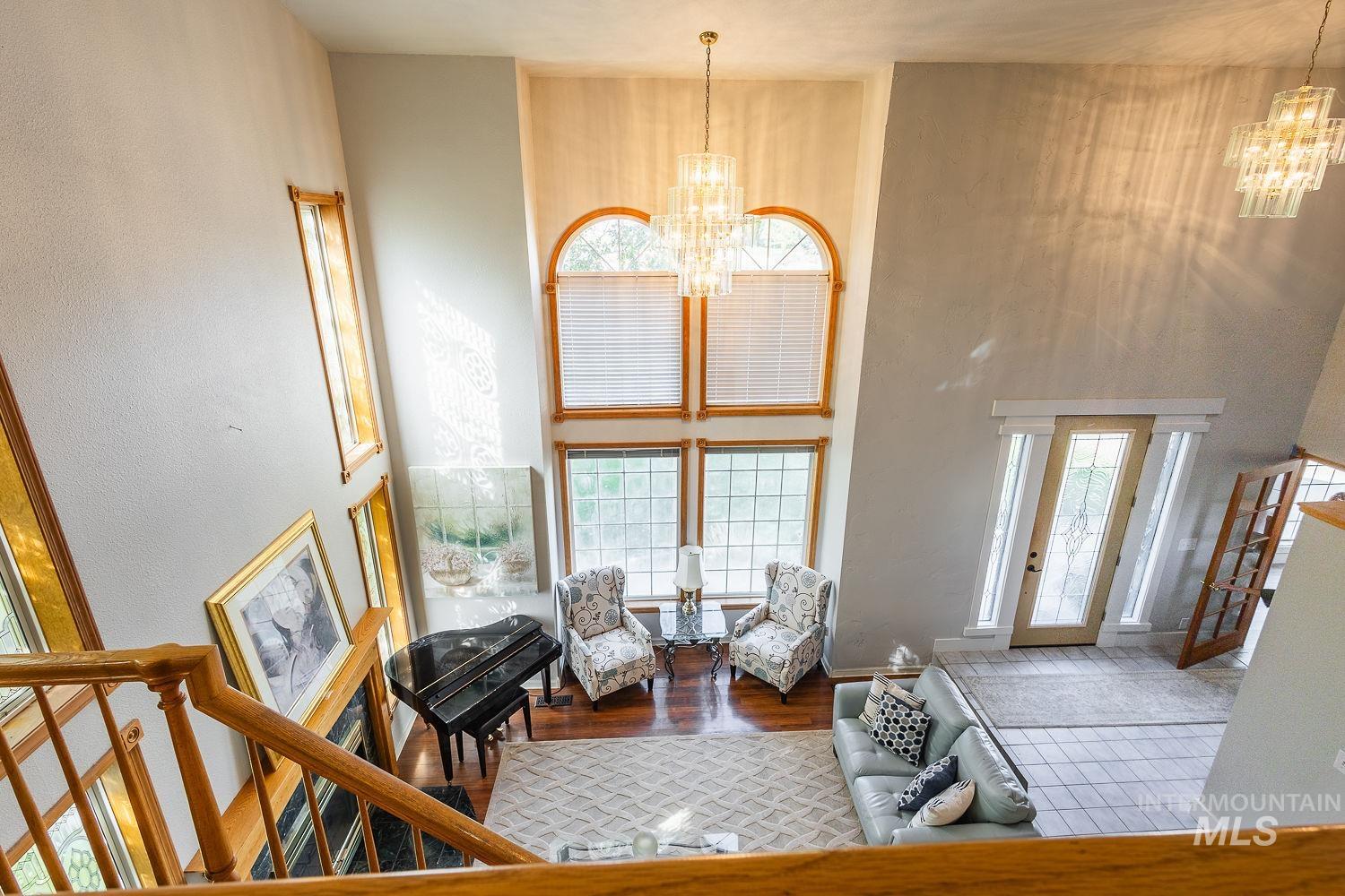 Living room featuring a chandelier, a towering ceiling, wood finished floors, and stairway
