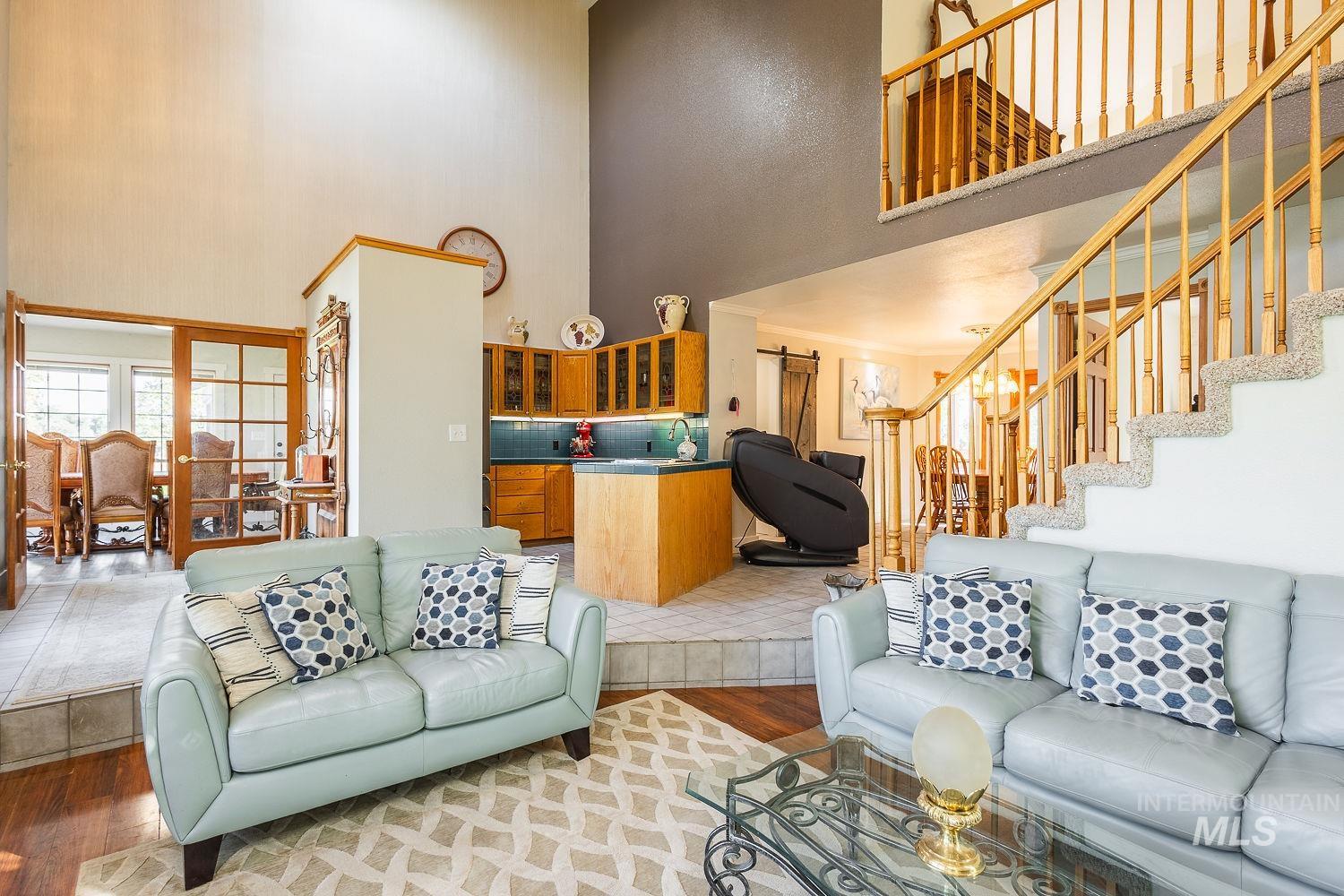 Living area featuring light wood finished floors, a high ceiling, and stairs