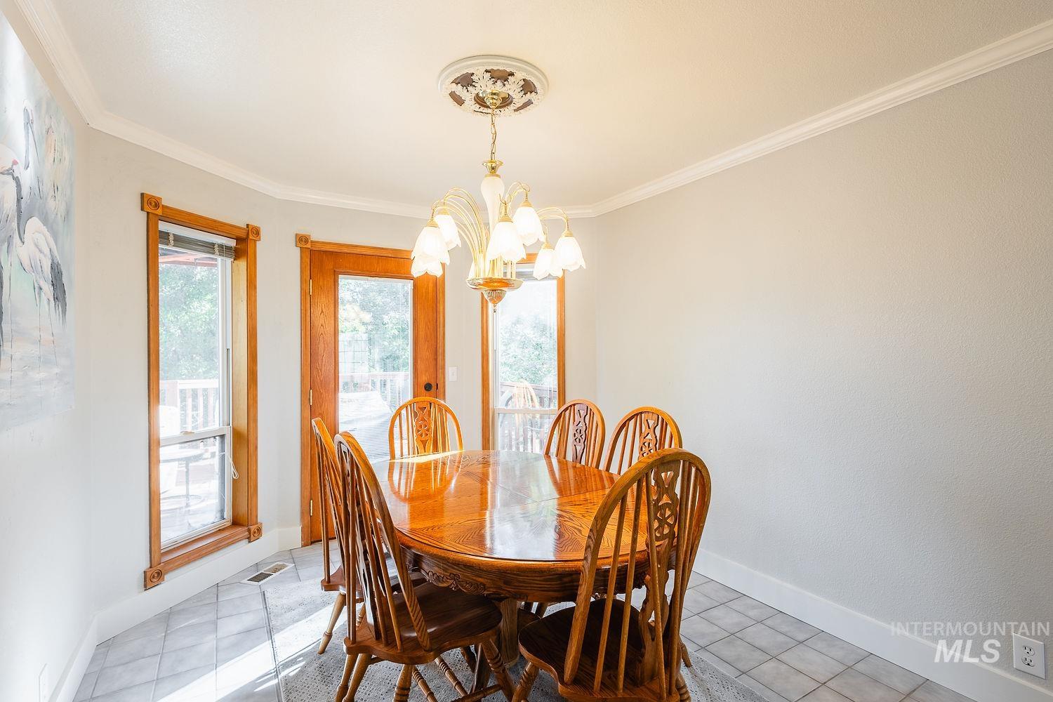 Dining space featuring crown molding, a chandelier, and tile patterned floors