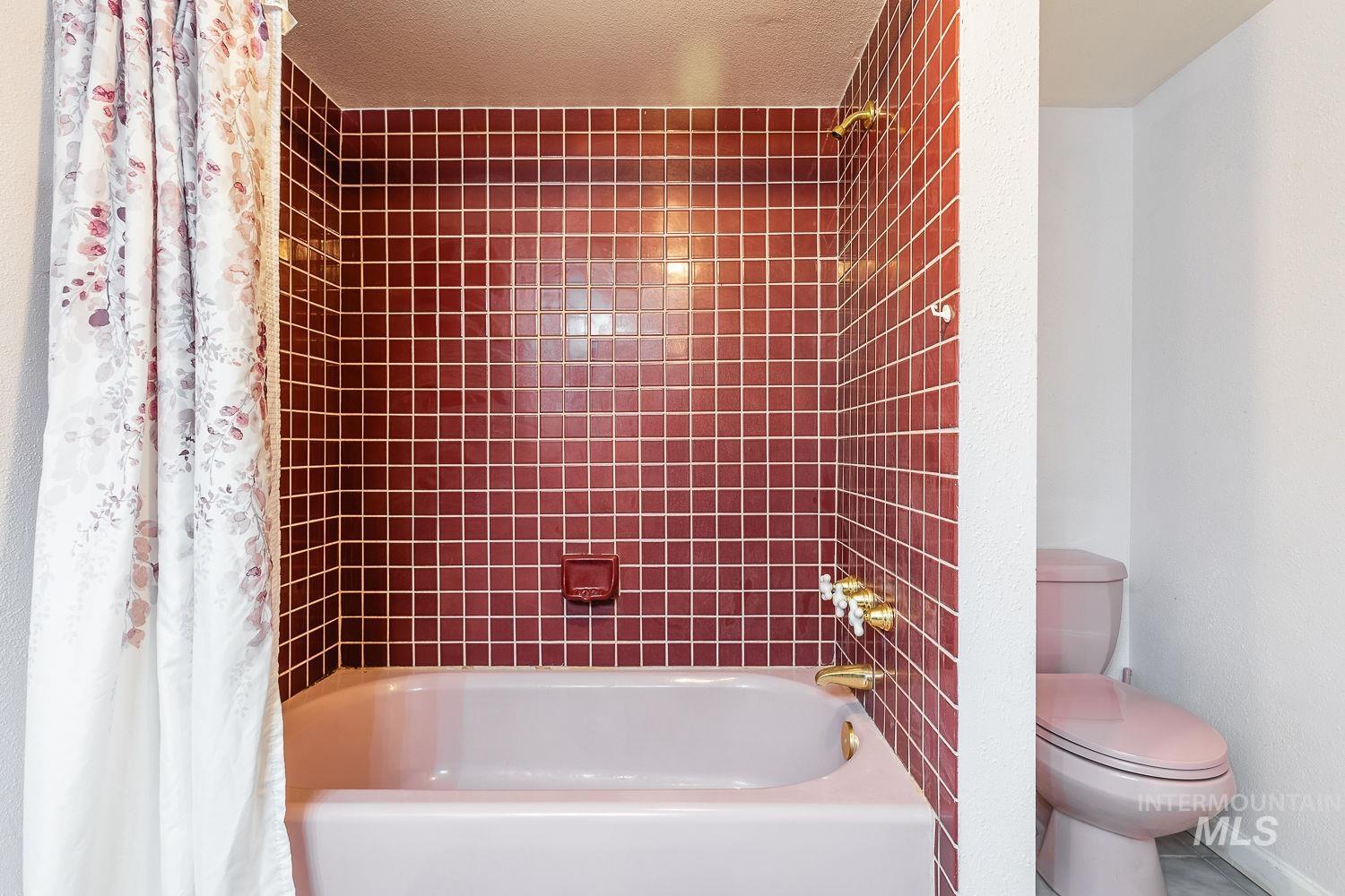 Bathroom featuring shower / tub combo with curtain and toilet