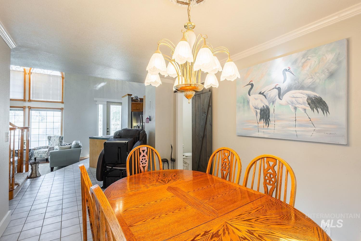 Dining area with tile patterned flooring, a chandelier, and ornamental molding