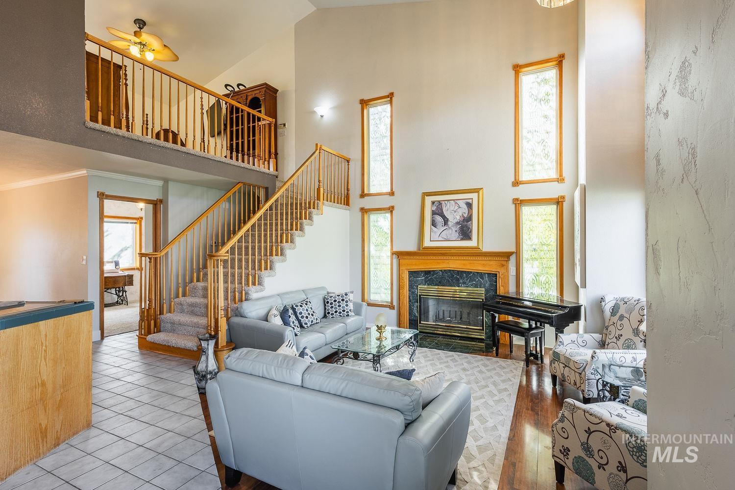 Featuring plenty of natural light, a towering ceiling, a high end fireplace, a ceiling fan, and wood finished floors