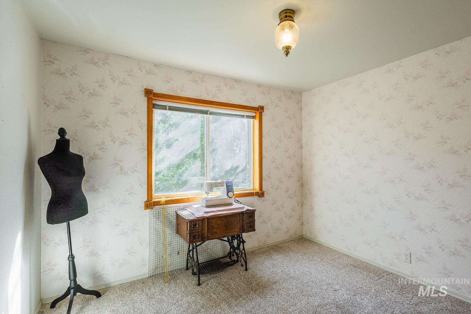 Carpeted empty room featuring wallpapered walls and baseboards
