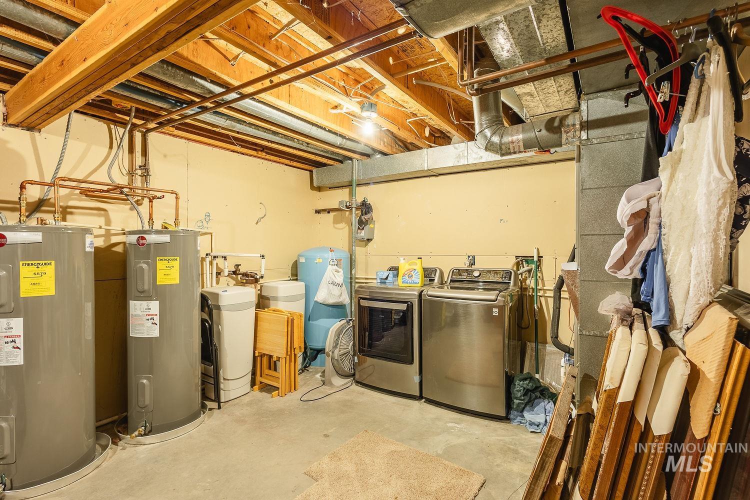 Unfinished below grade area featuring water heater, a water softener system, a water pressure tank, and separate washer and dryer